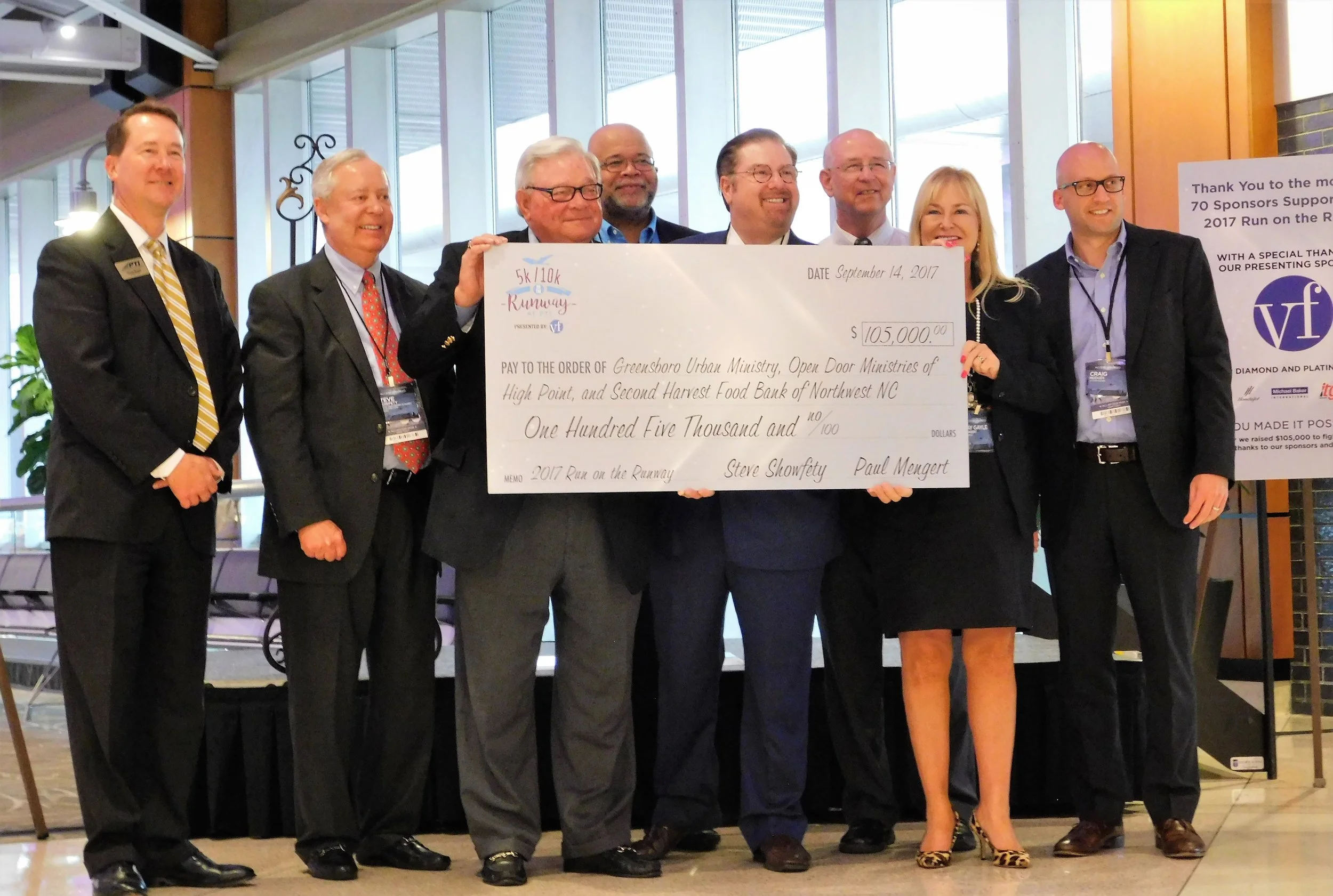 Paul K. Mengert and May Gayle Mengert of AMG Present “Run on the Runway” Fundraiser Check of $100,000 to Hunger-Relief Beneficiaries.