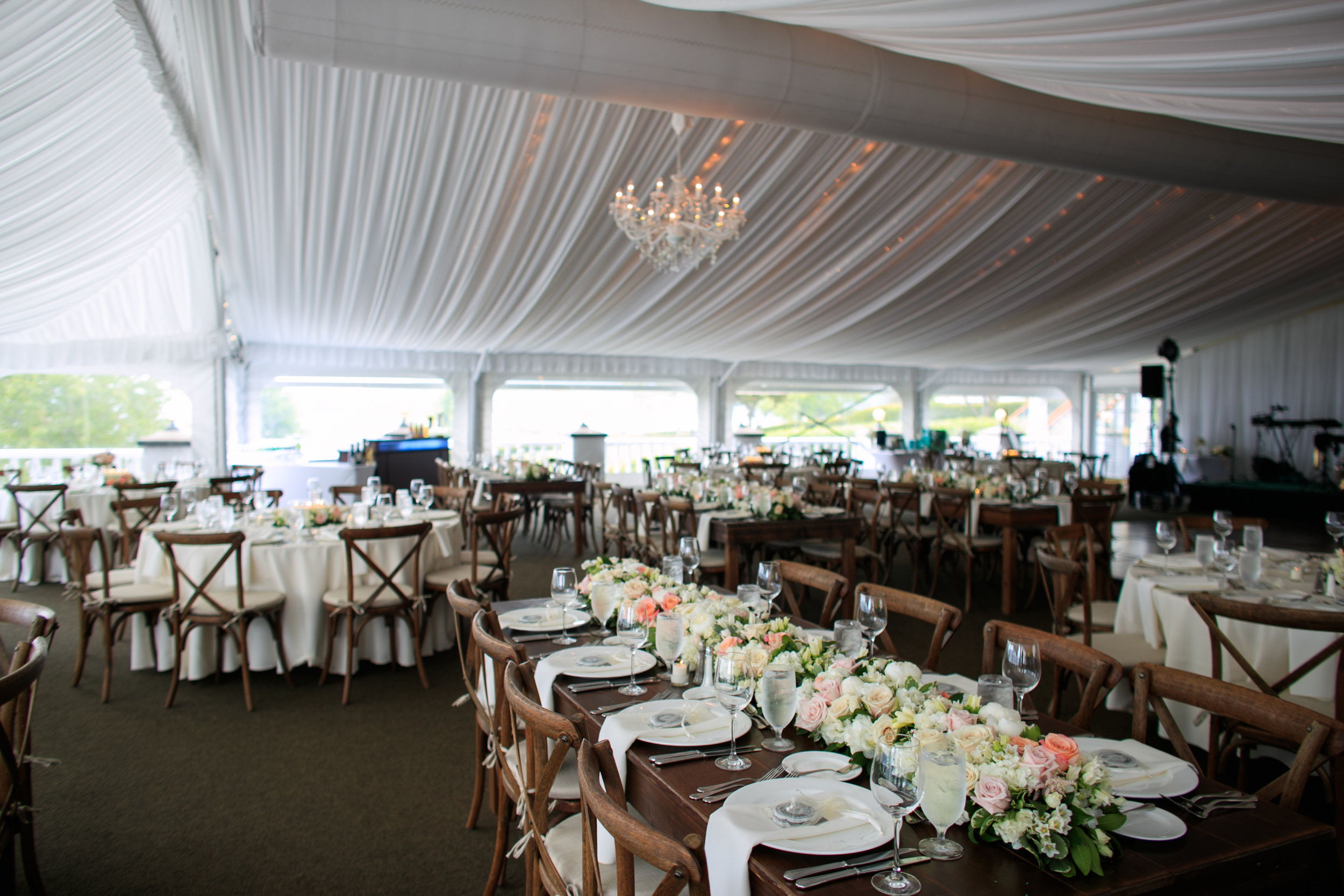  chandeliers, chargers and farm tables used for a tent wedding reception 