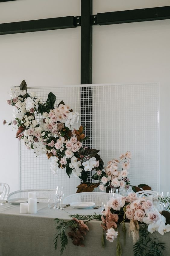 an-ultra-modern-white-mesh-backdrop-with-blush-and-white-blooms-dark-foliage-and-magnolia-leaves.jpg