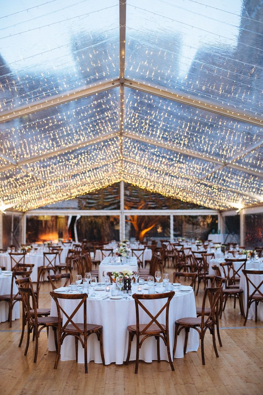 10m x 35m Clear Wedding Marquee with round tables, cross back chairs, fairy lights and wooden flooring.jpg