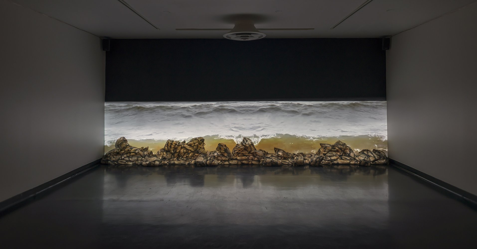 Shoreline, digital photographs printed on bags of recycled polyester, sand, cable ties, video projection, 570cm x 122cm x 30cm (photo: Ernest Mayer)