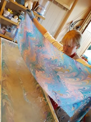 My husband helps me lay the prepared scarf onto the paint: the pattern prints directly onto the silk