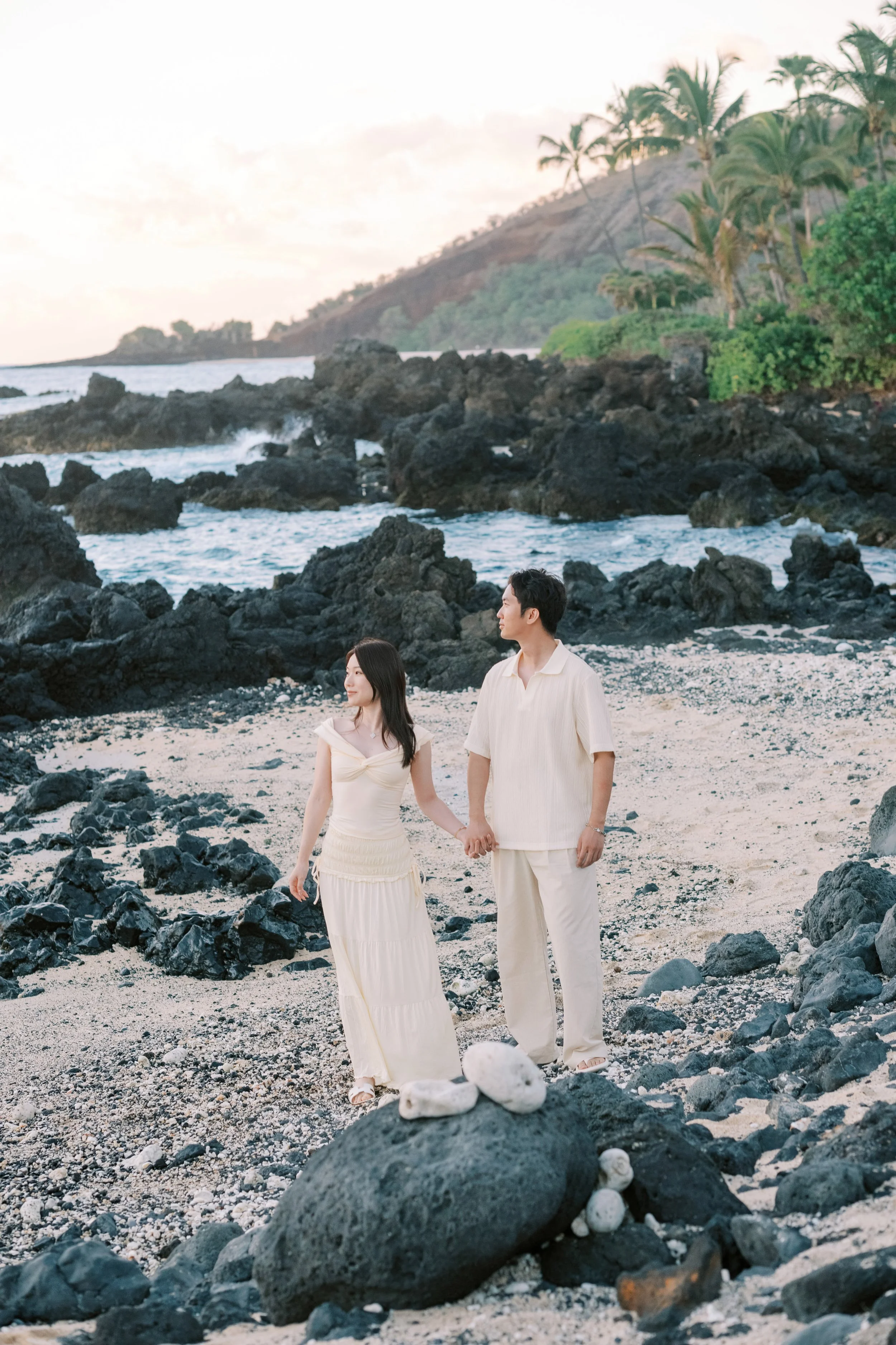 A couple walking hand in hand along the shoreline at the White Orchid Beach House.