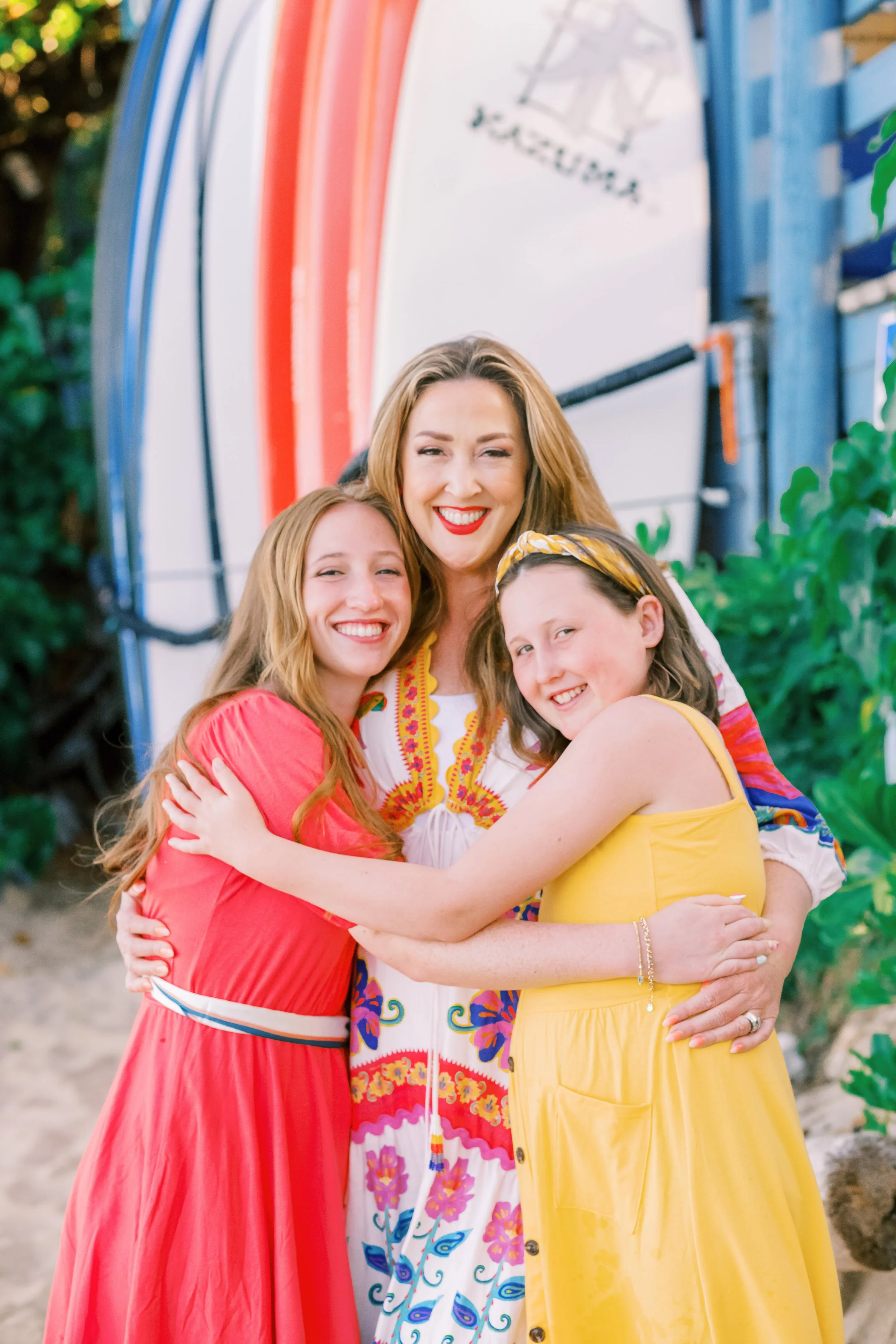 A mother and her daughters standing in front of surfboards at Kaplaua Bay during a morning photoshoot.