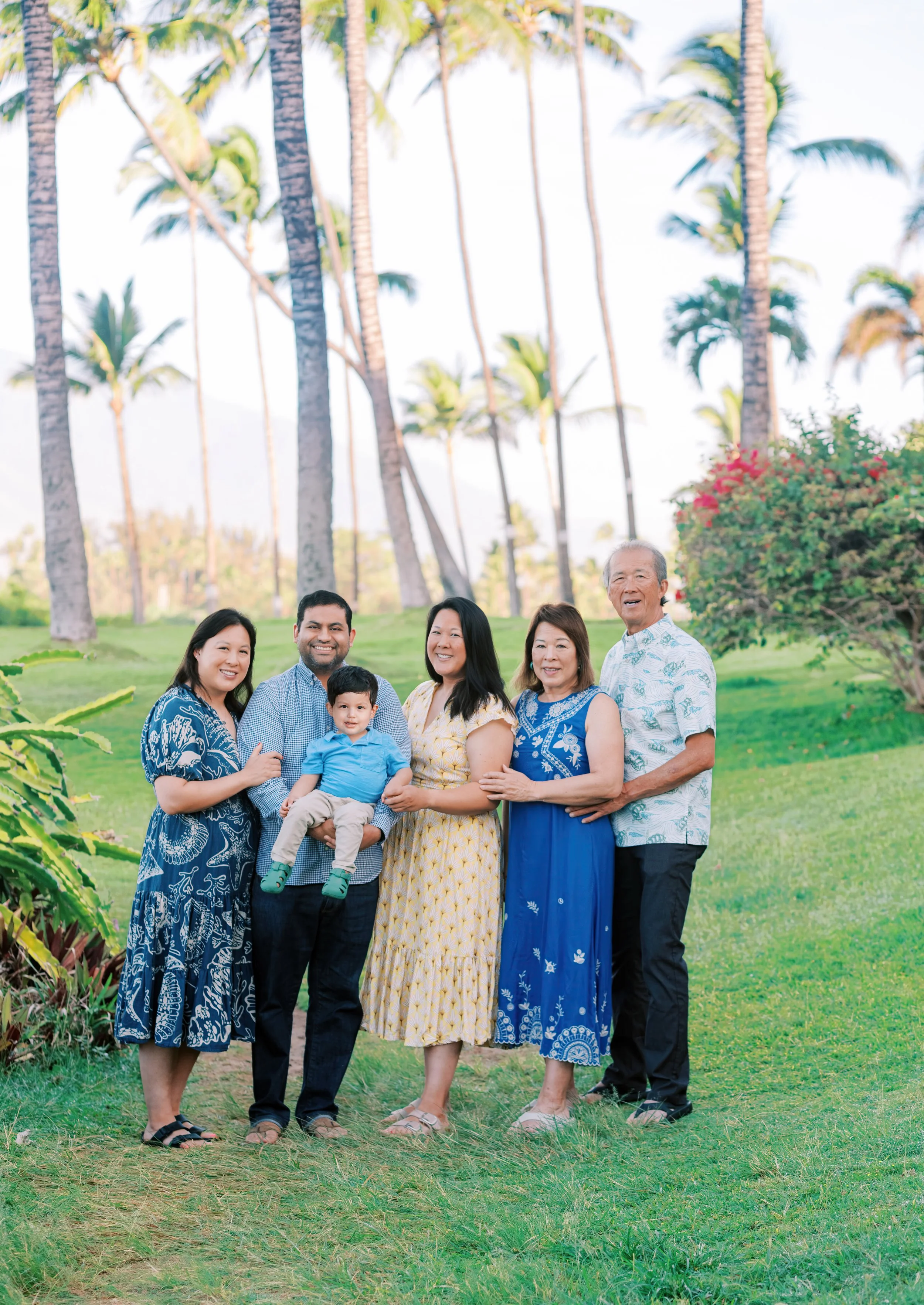 Family of five holding a toddler in palm tree grove during Maui family vacation photography session in Kihei.