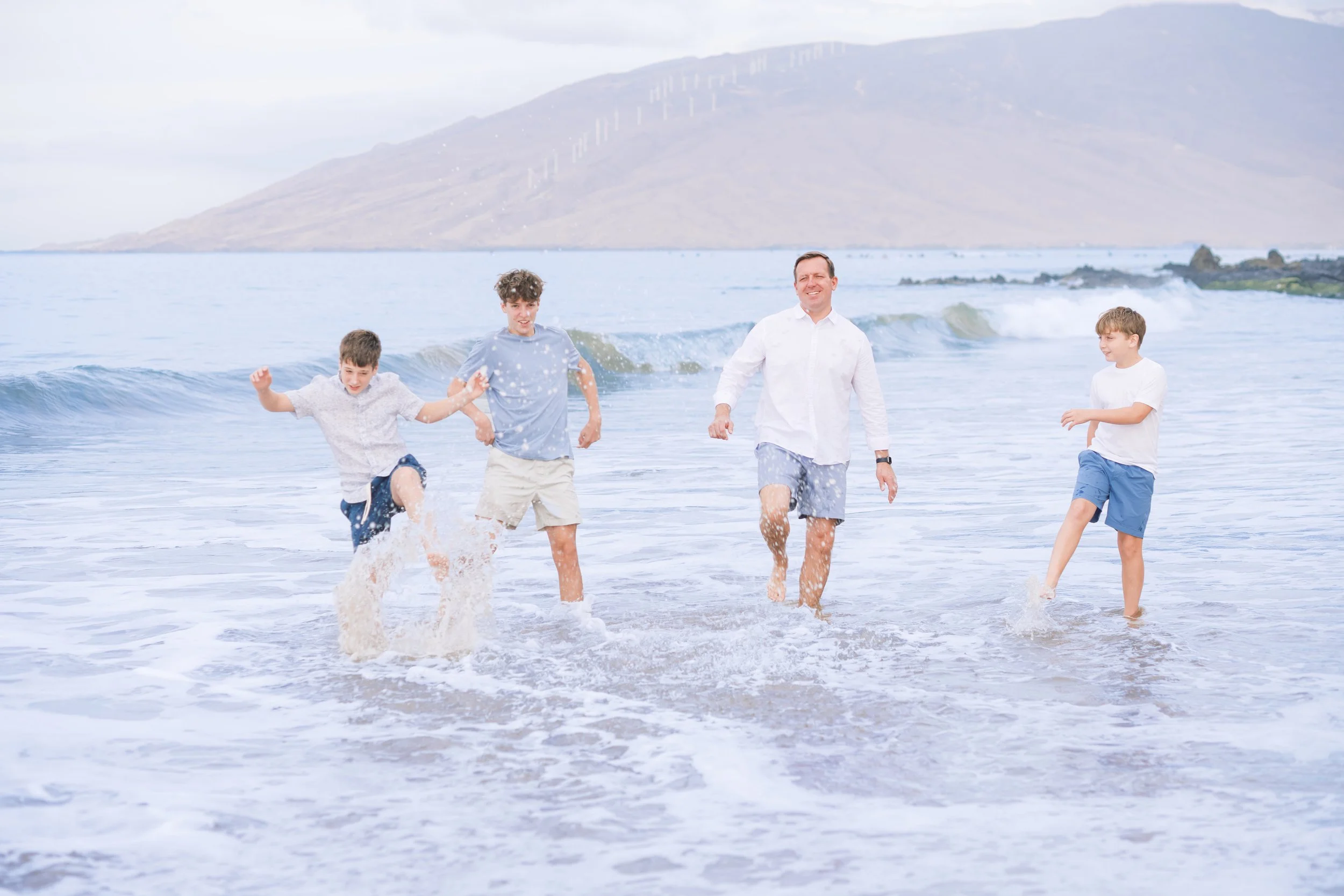 A family splashing in the ocean during a family photoshoot in Kihei Maui.