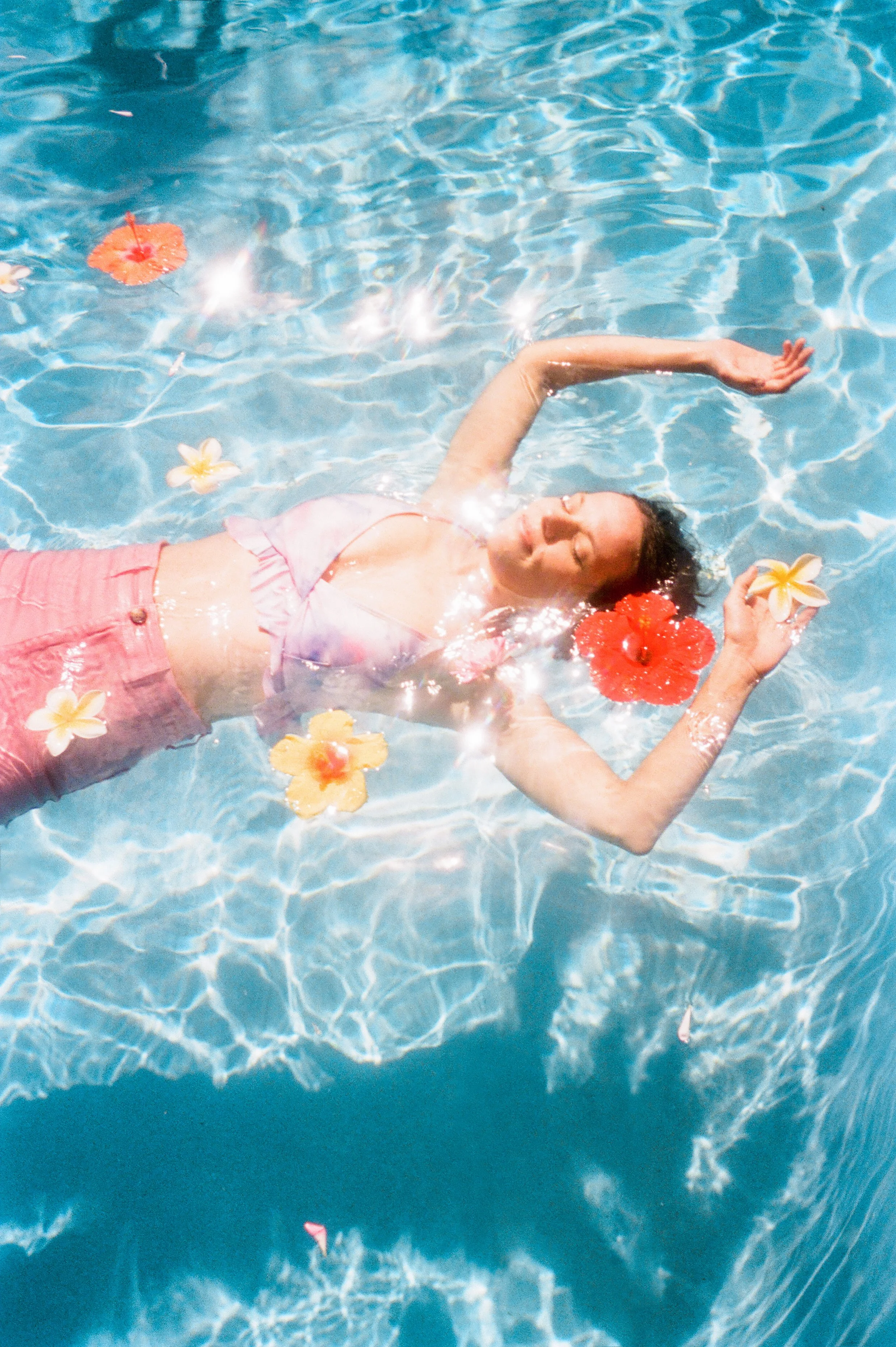 Maui family portrait photographed on 35mm film in the water surrounded by tropical flowers.