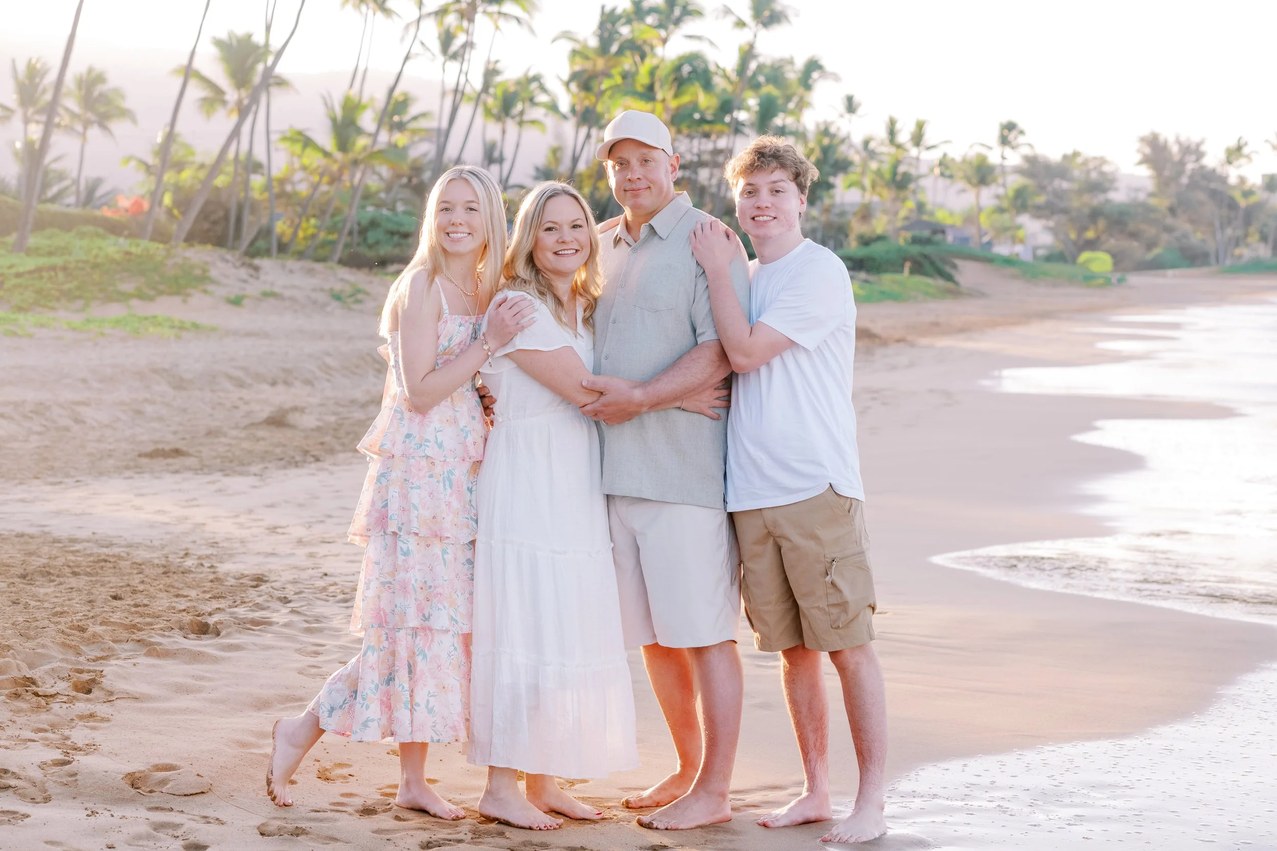 A family photoshoot on a sandy beach in Kihei Maui with palm trees in the background.