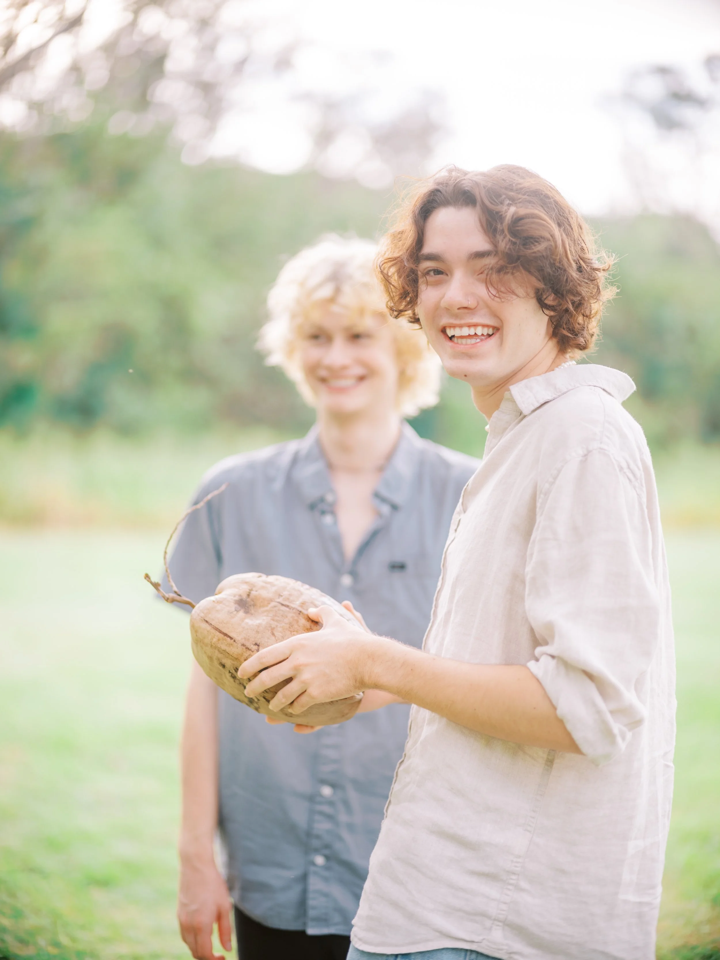 Holding a coconut under palm trees for a tropical senior photoshoot in Oahu Hawaii.