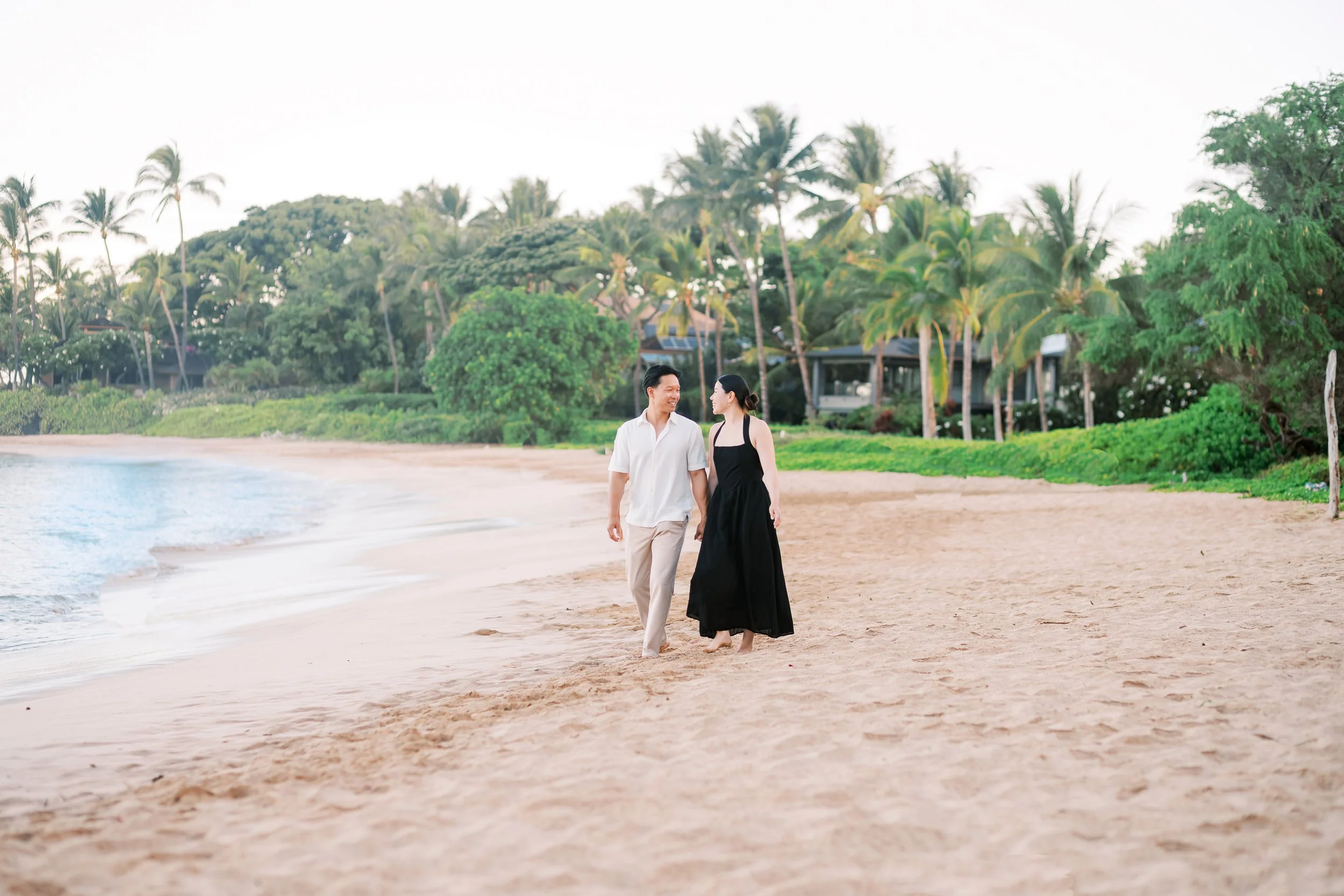 A couple hand in hand strolling the shoreline of Palauea Beach in Maui during a sunrise photoshoot in Wailea.