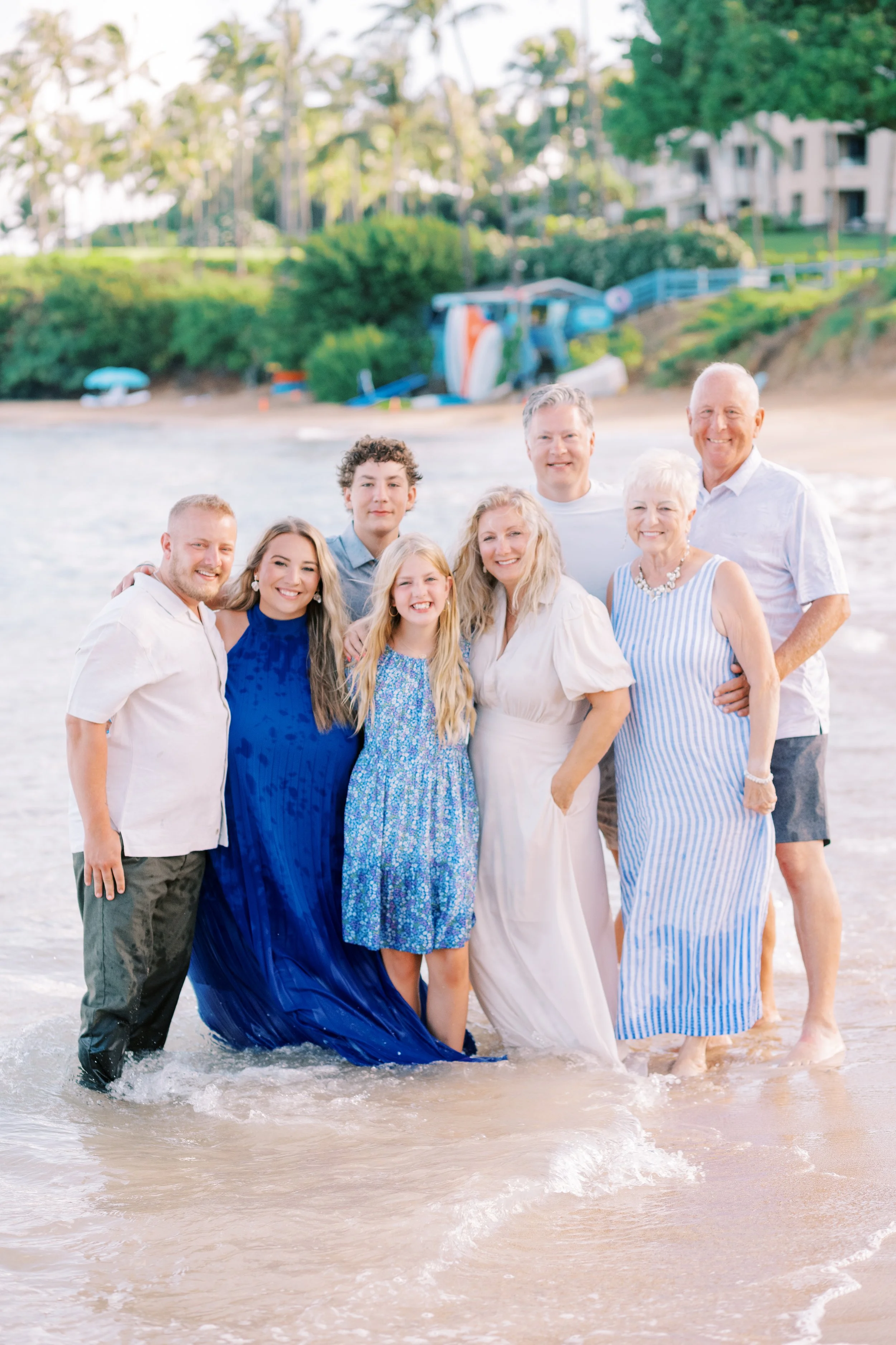 A family photoshoot in Kapalua with a family standing in the ocean smiling on Maui.