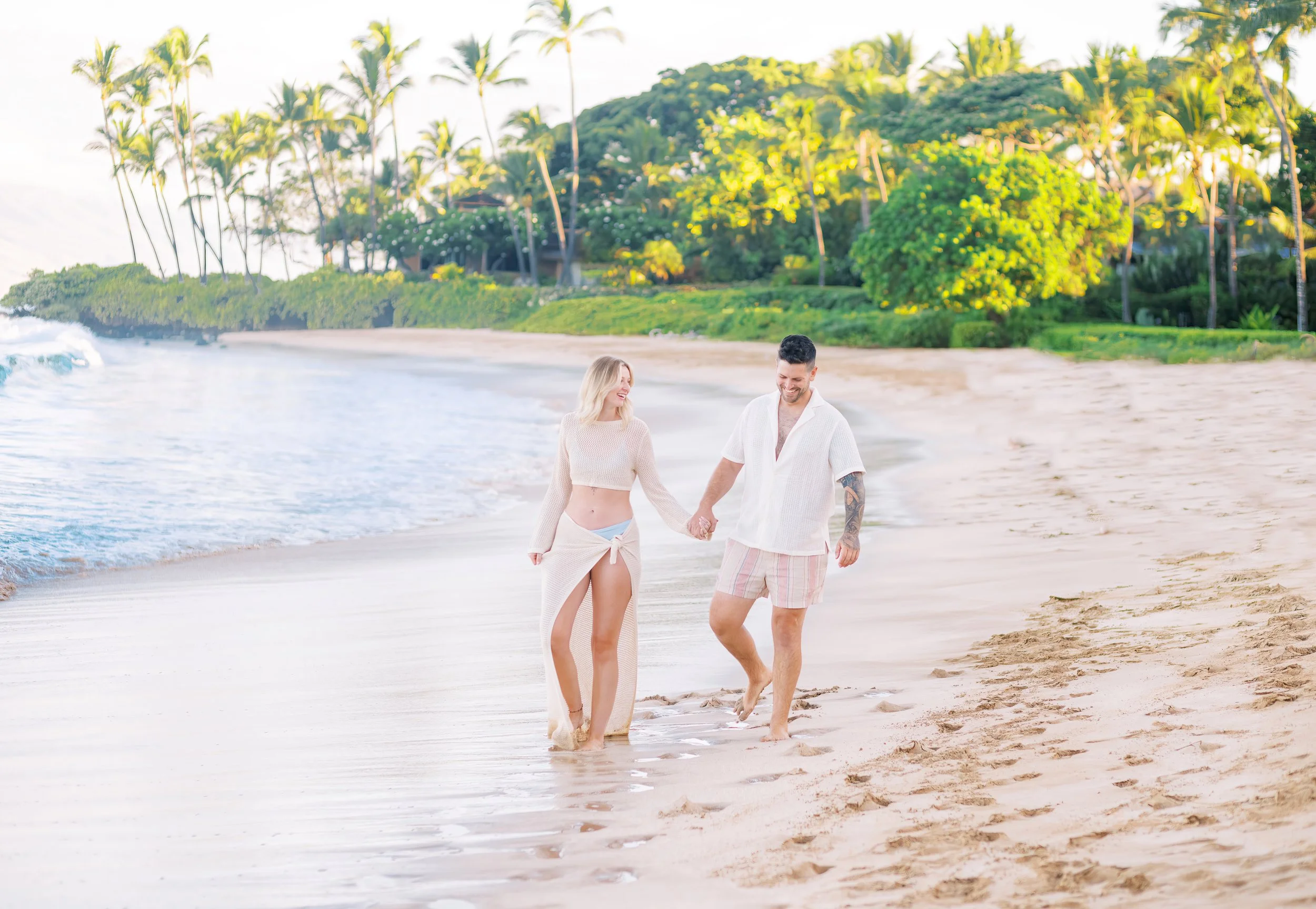 A couple holding hands walking at Palauea Beach aka White Rock at sunrise on Maui.