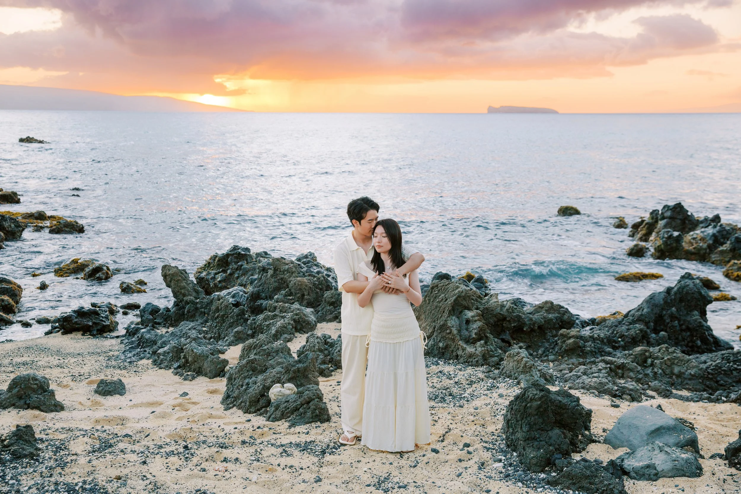 A couples proposal at White Orchid Beach House on Maui captured during a vibrant sunset.
