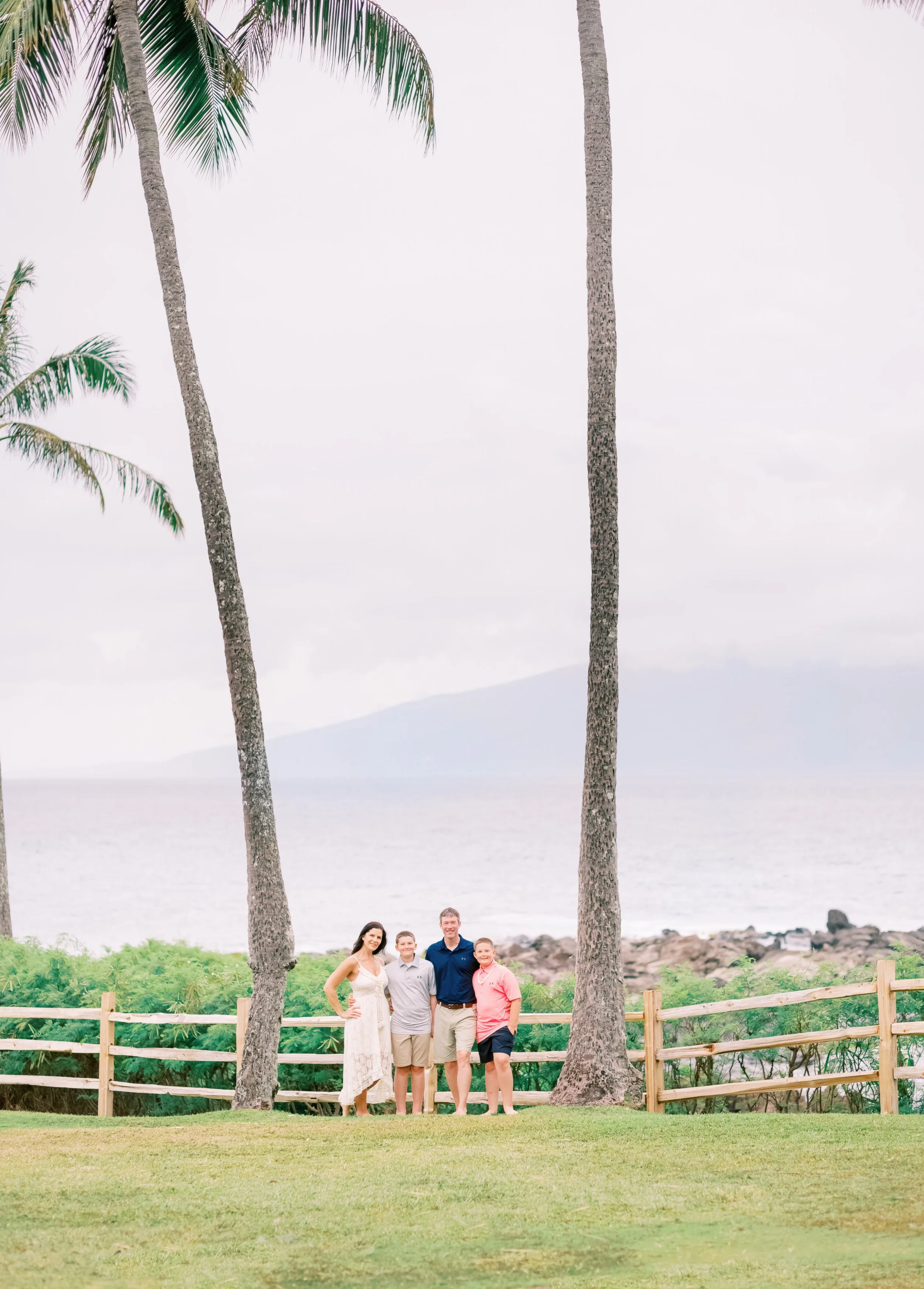 A family standing under tall palm trees by The Montage at Kapalua Bay during a photoshoot.