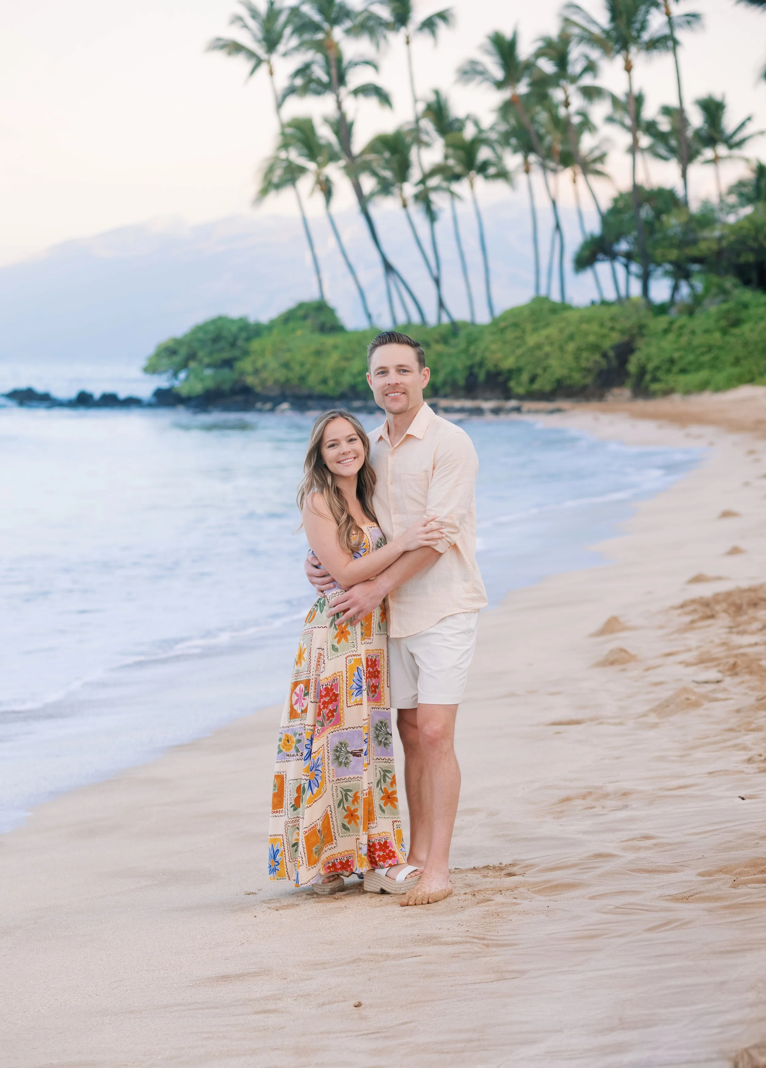 A couple standing on the sand in the early morning for an engagement photoshoot at Palauea Beach aka White Rock in Maui.