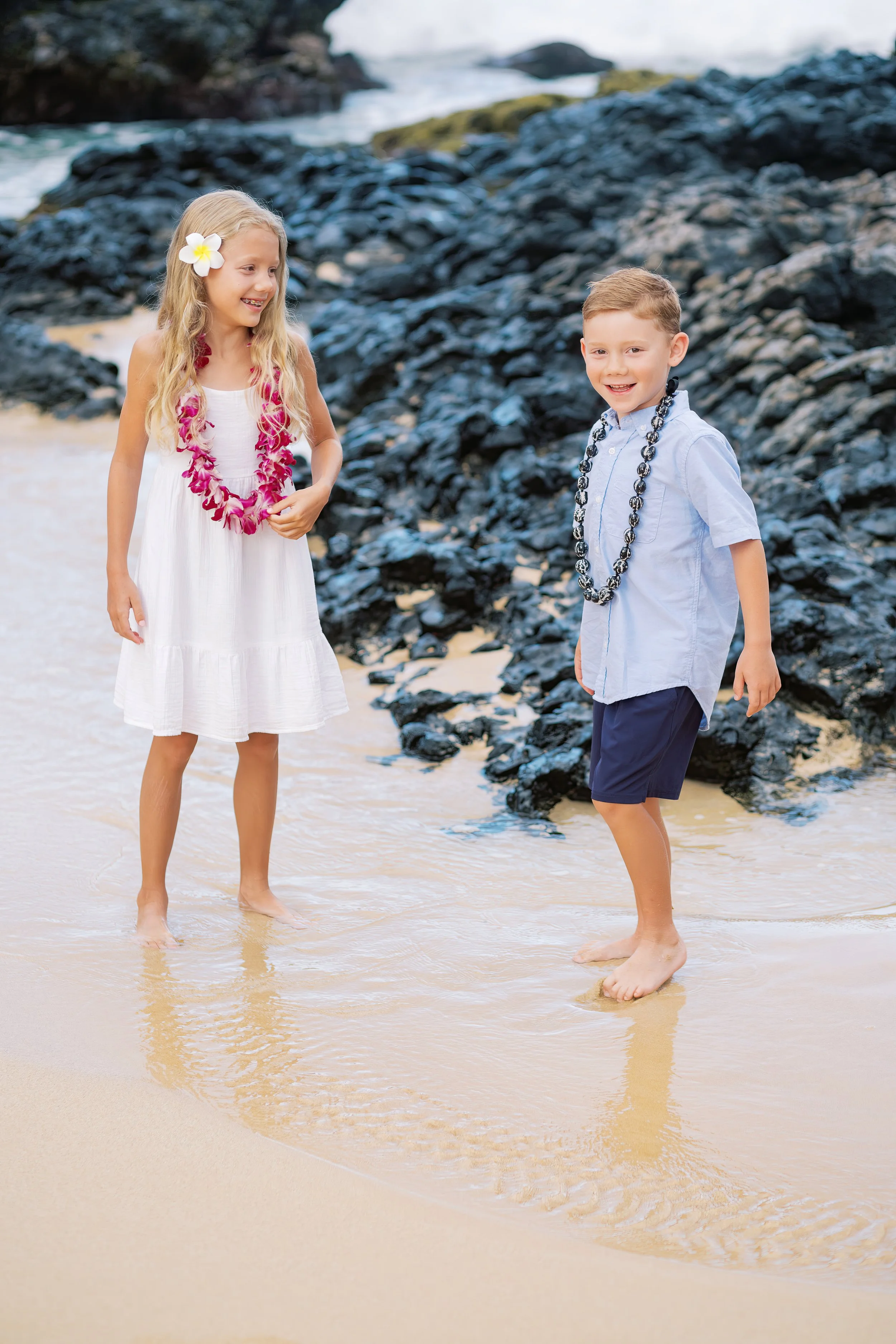 Two children playing and laughing at Makena Cove in the ocean during a family photoshoot.
