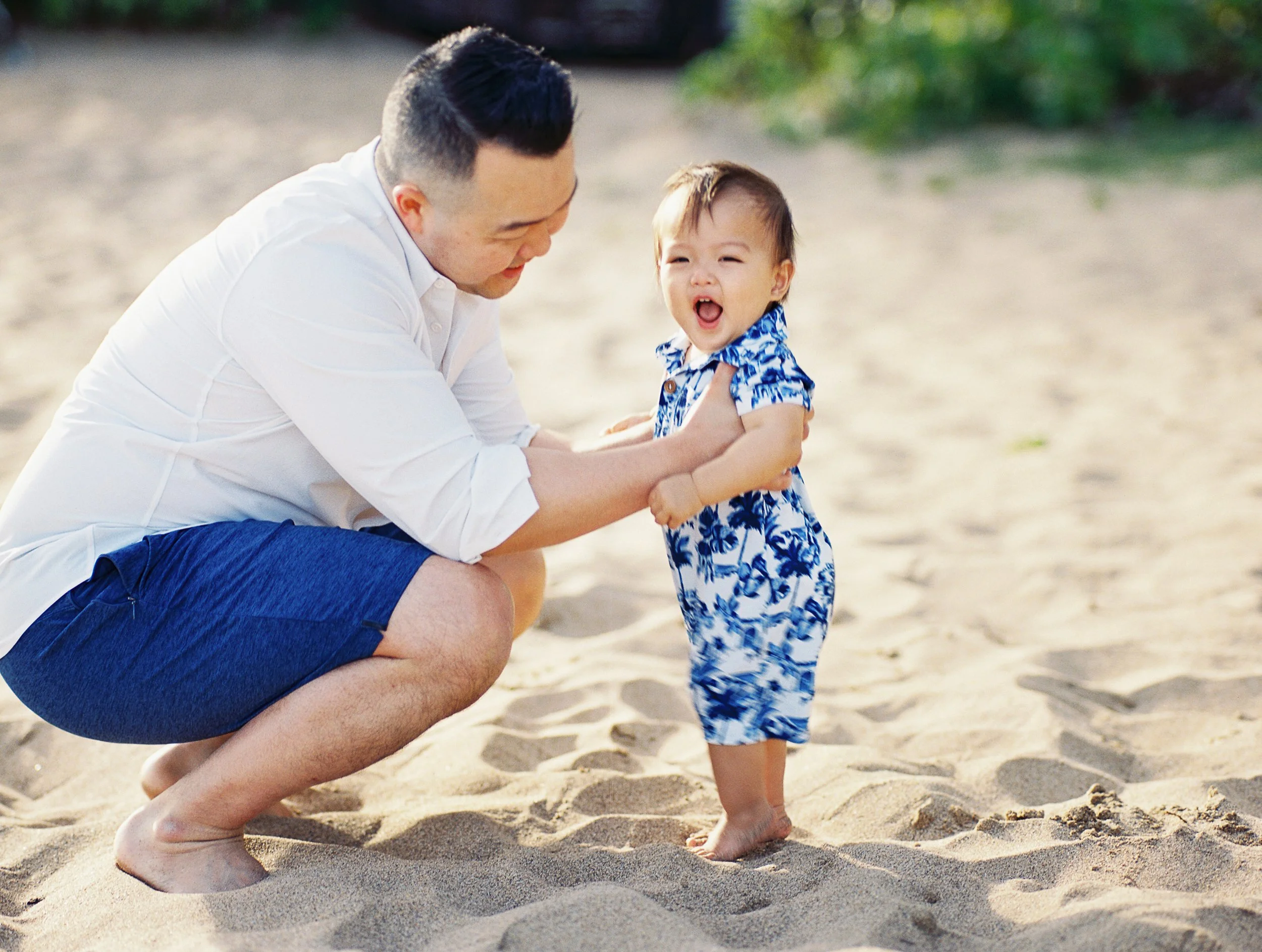 A baby smiling with toes in the sand on a beach in Maui captured on film