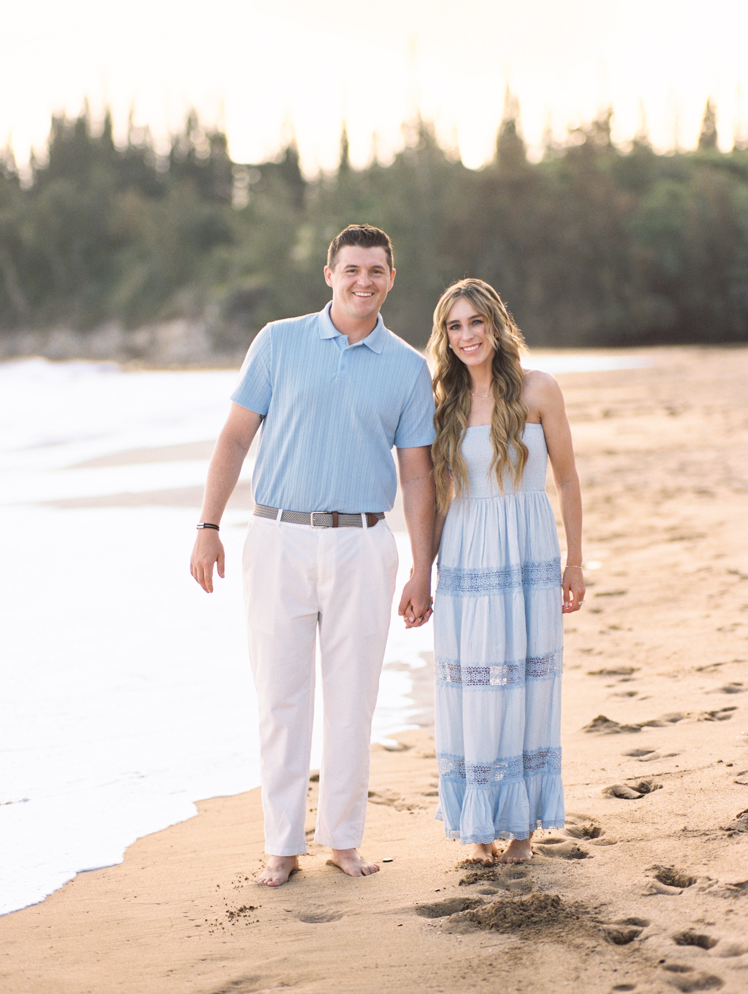 A couple standing hand in hand during a morning photoshoot at D.T. Flemings Beach in Kapalua Maui.