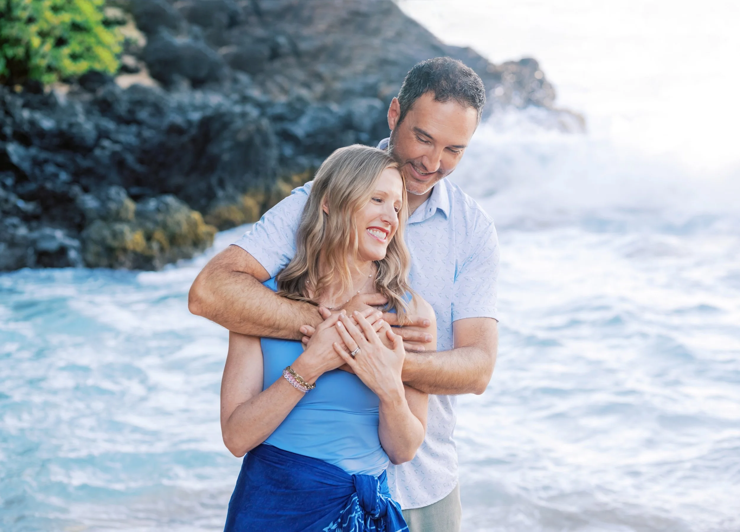 A couple embracing in the ocean at sunrise at Maui's Makena Cove.
