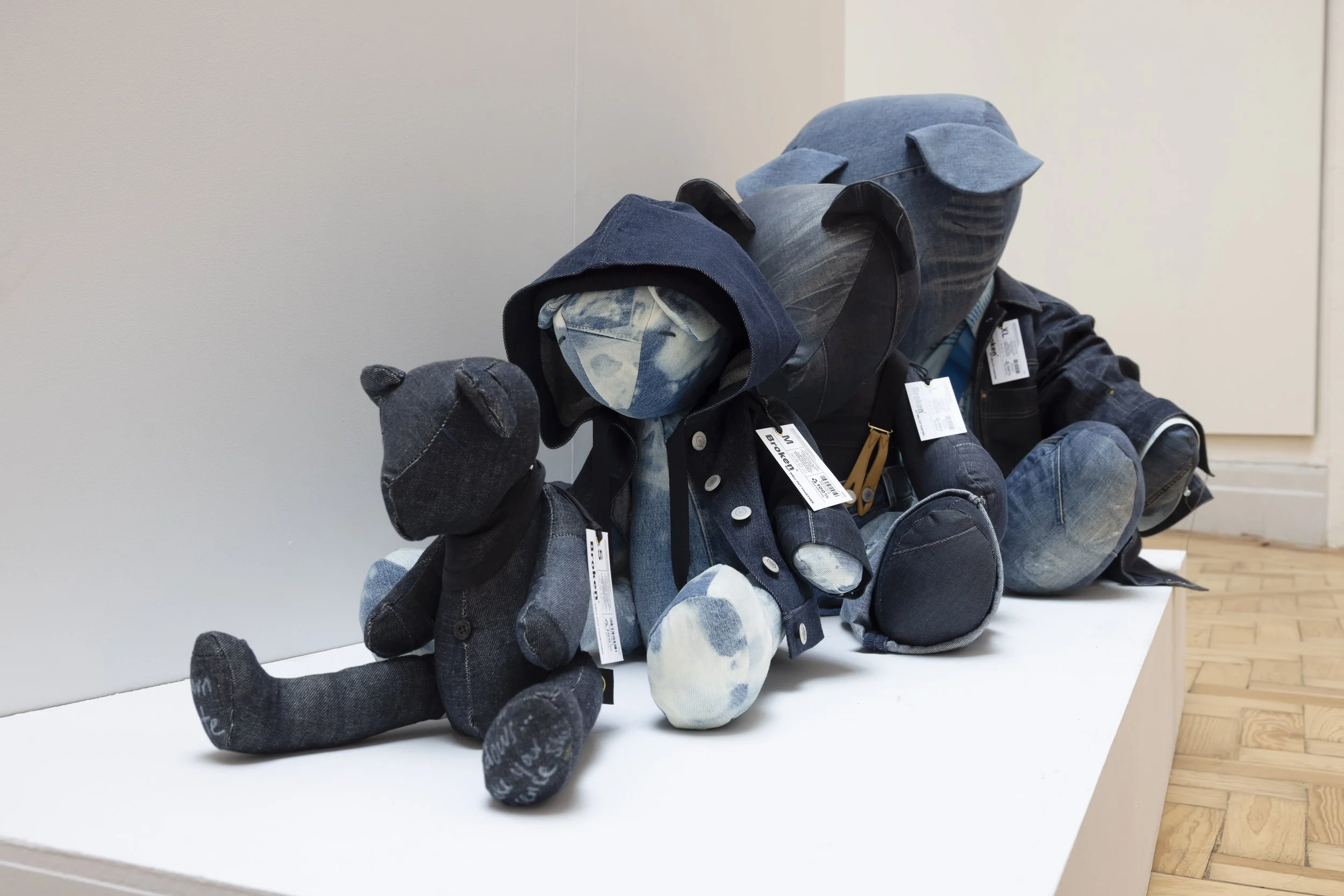Four denim teddy bear sculptures arranged in increasing sizes in the Holden Gallery at Manchester Metropolitan University's More to Come degree show.