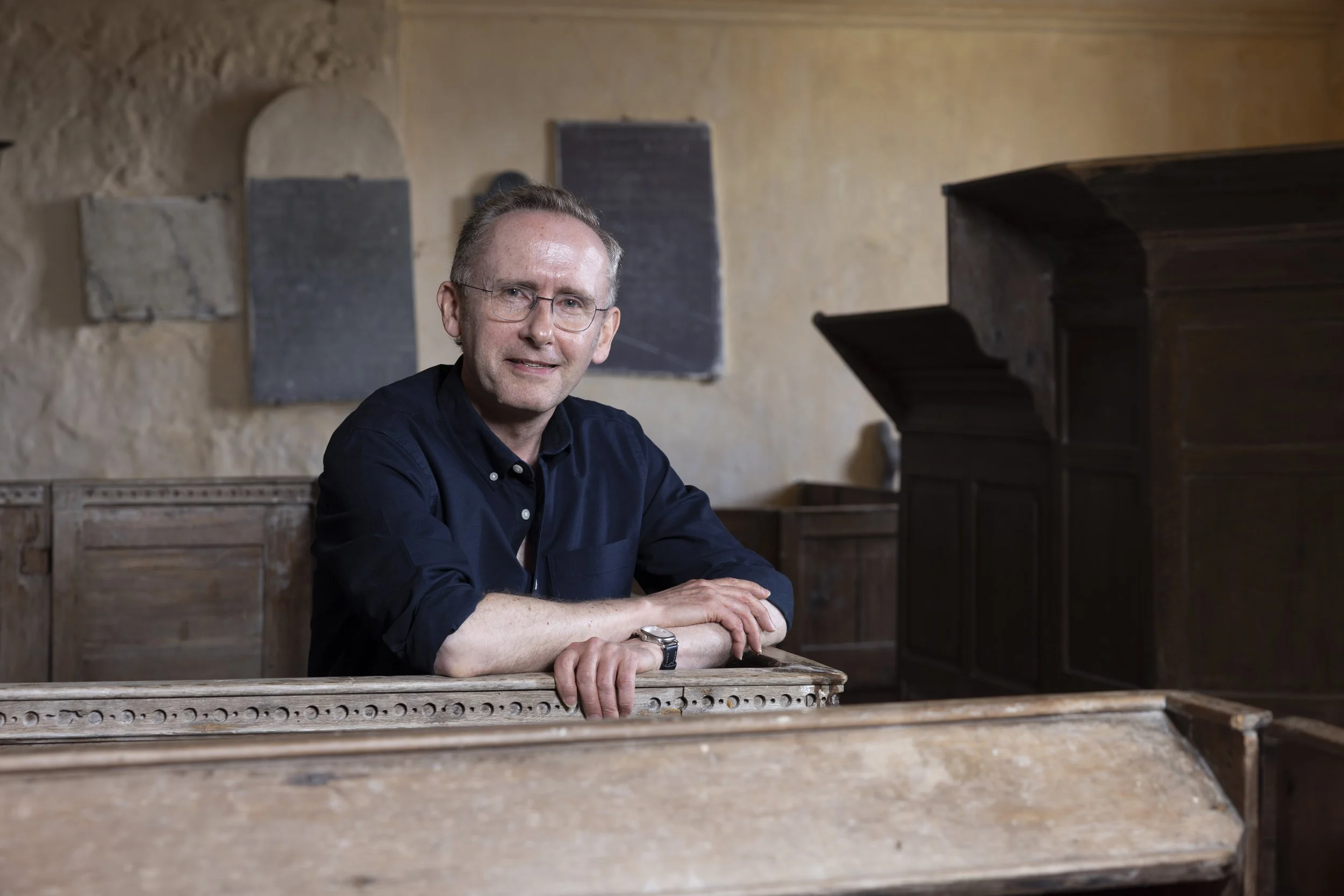 David Farrington sitting inside one of the historic box pews at St Baglan’s Church.