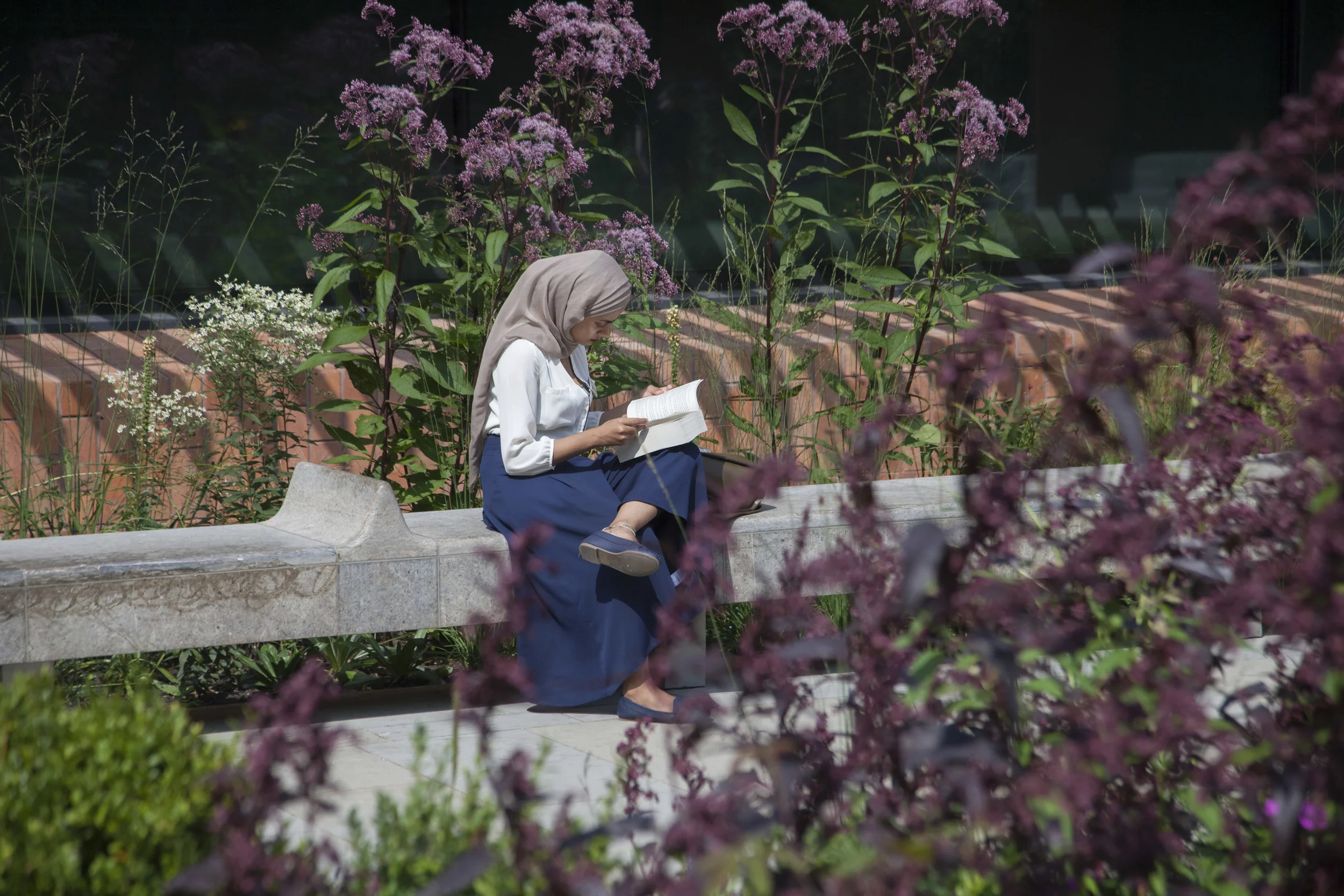 A woman reading in a garden outside an art gallery in Manchester. Photographer David Oates