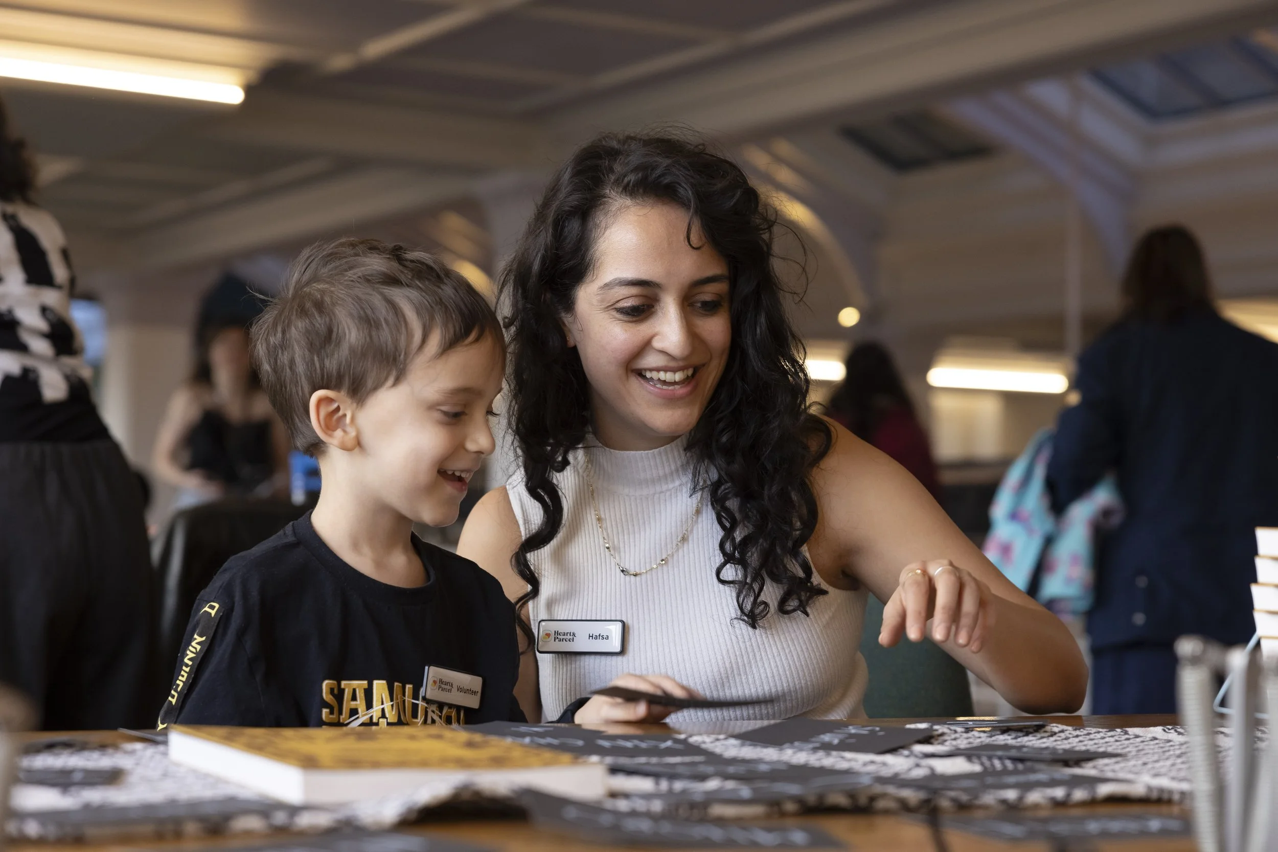 Young woman guiding a small child through a language workshop activity at a museum event.