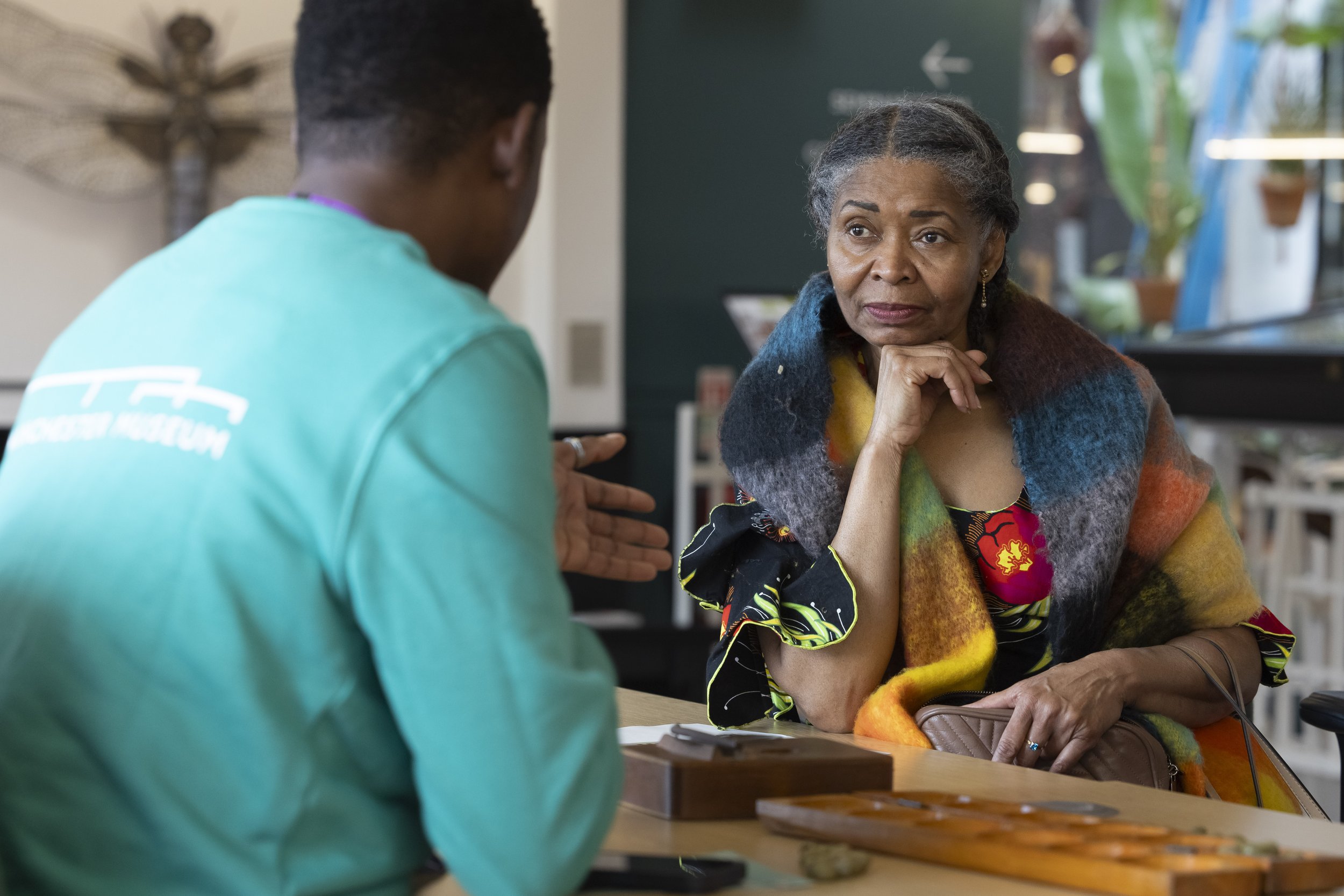  Afro-Caribbean woman speaking with a volunteer during a public event at Manchester Museum. 