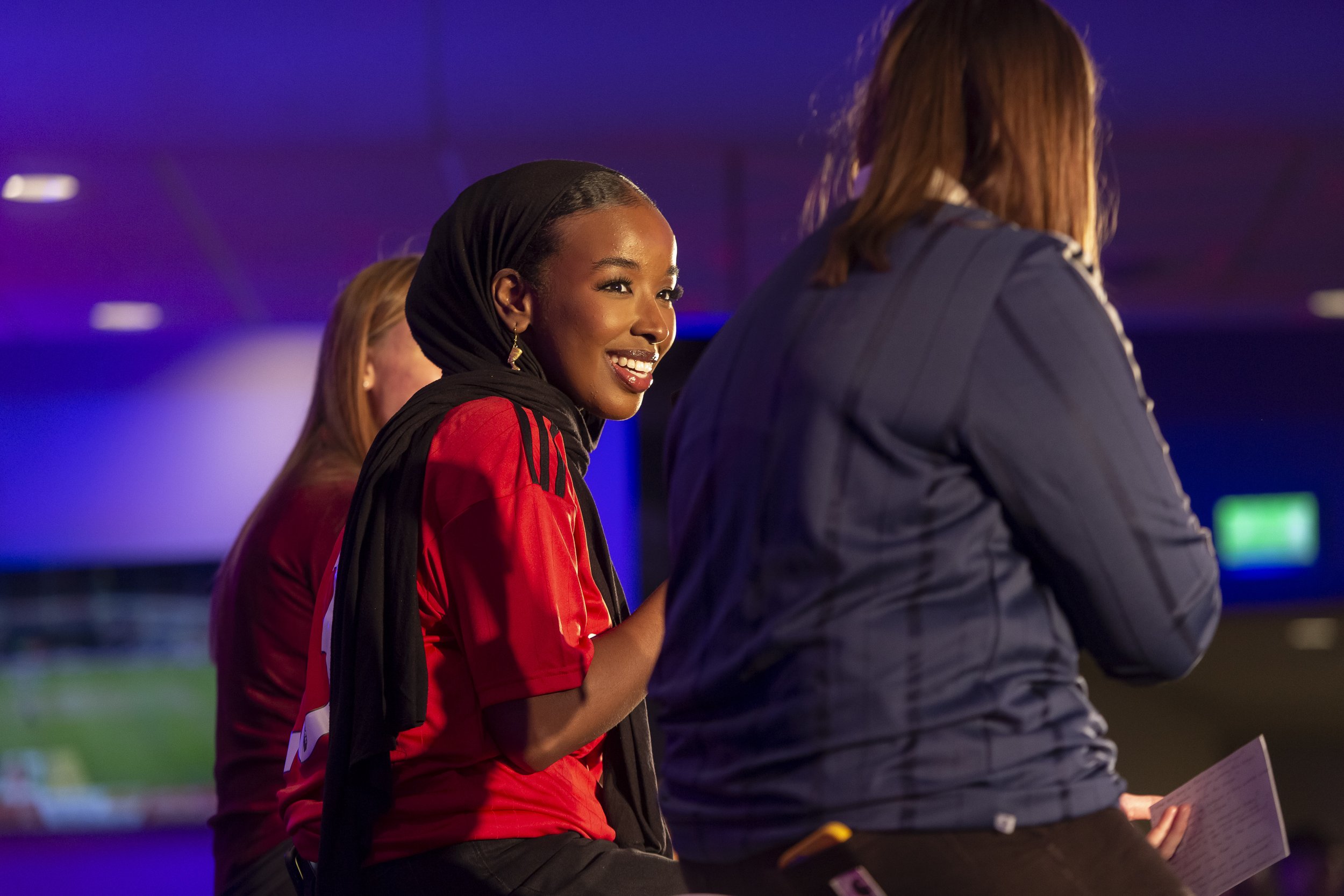  A photograph of an event for adidas in Old Trafford, Manchester in which a woman in a group conversation on stage is photographed smiling   