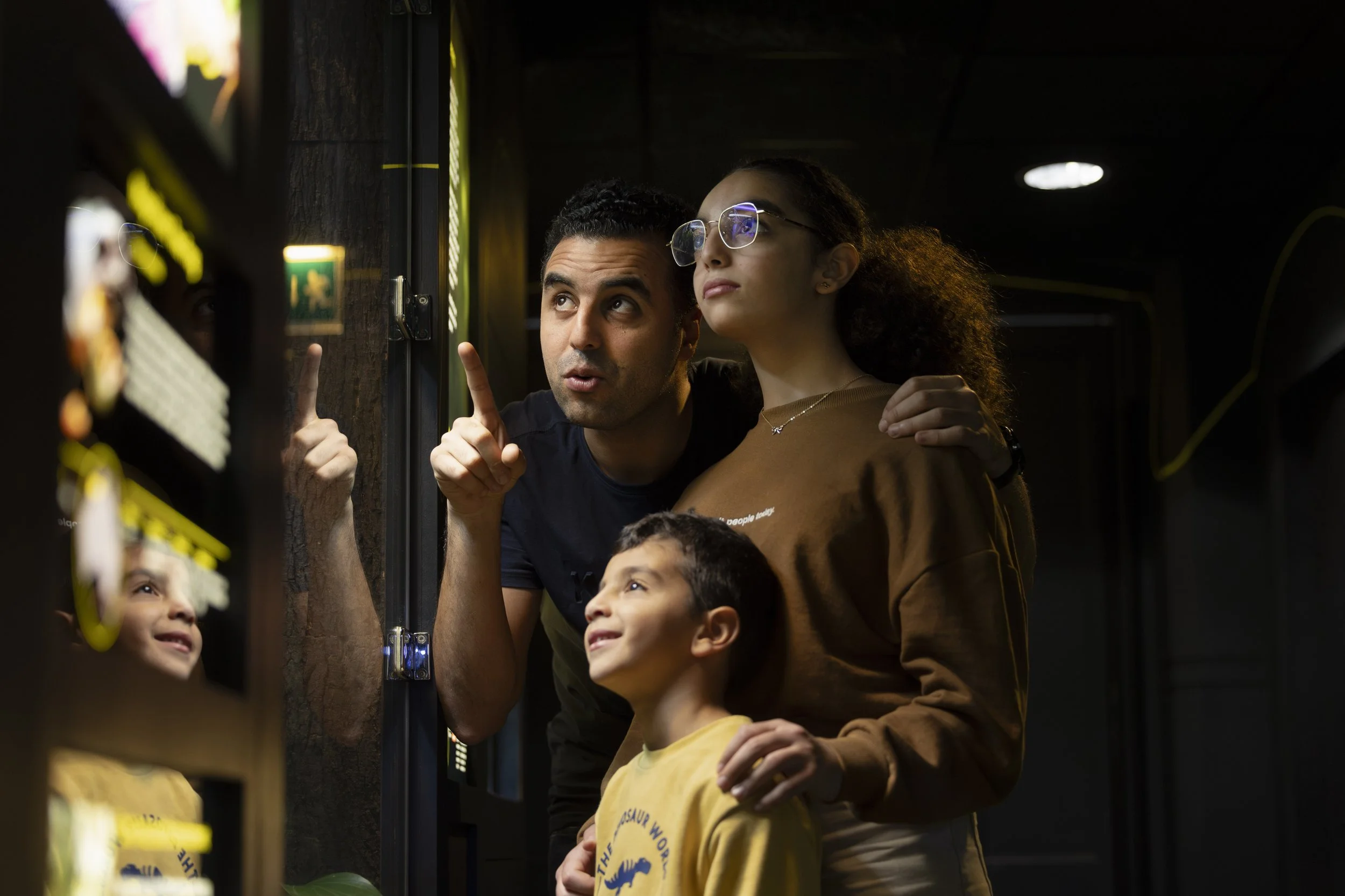  Family observing and discussing exhibits in a terrarium during a public event at Manchester Museum. 