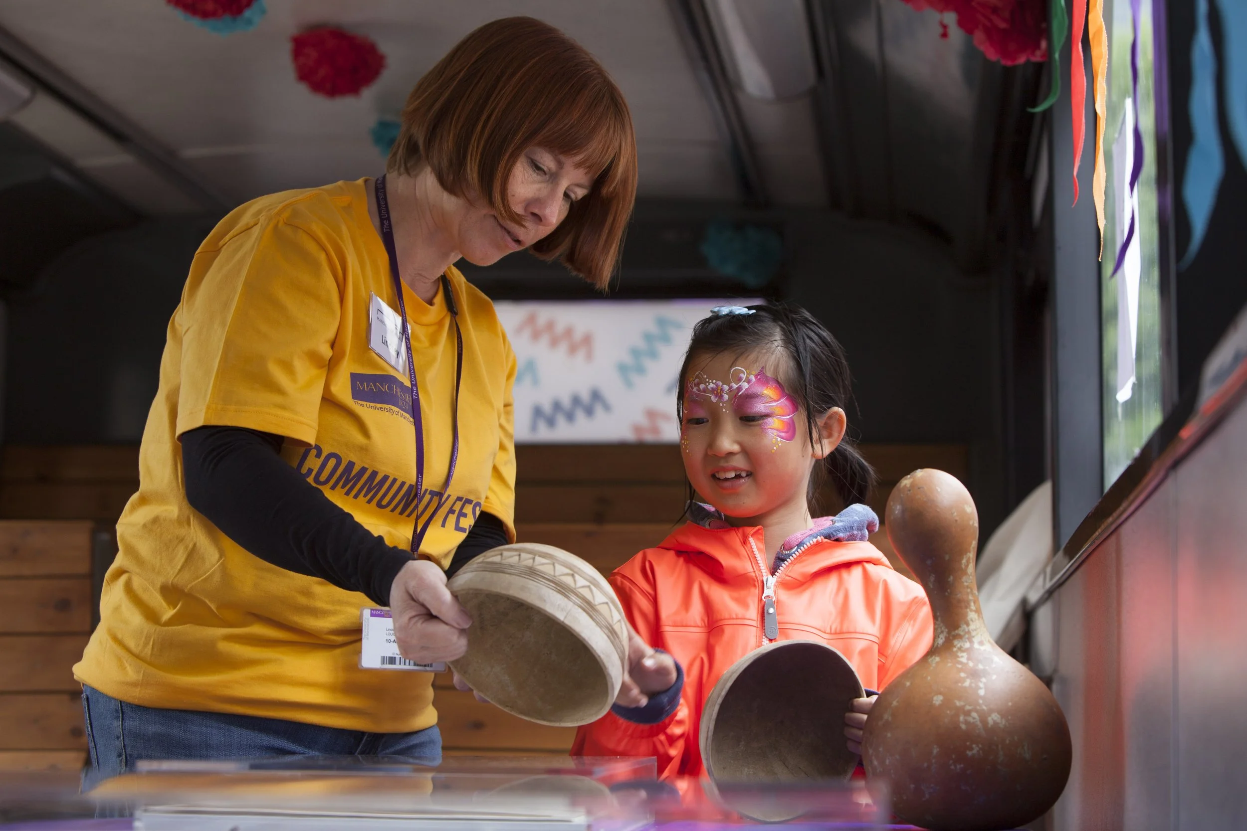  A museum assistant shows ceramics to a young visitor to Manchester Museum with a painted face 