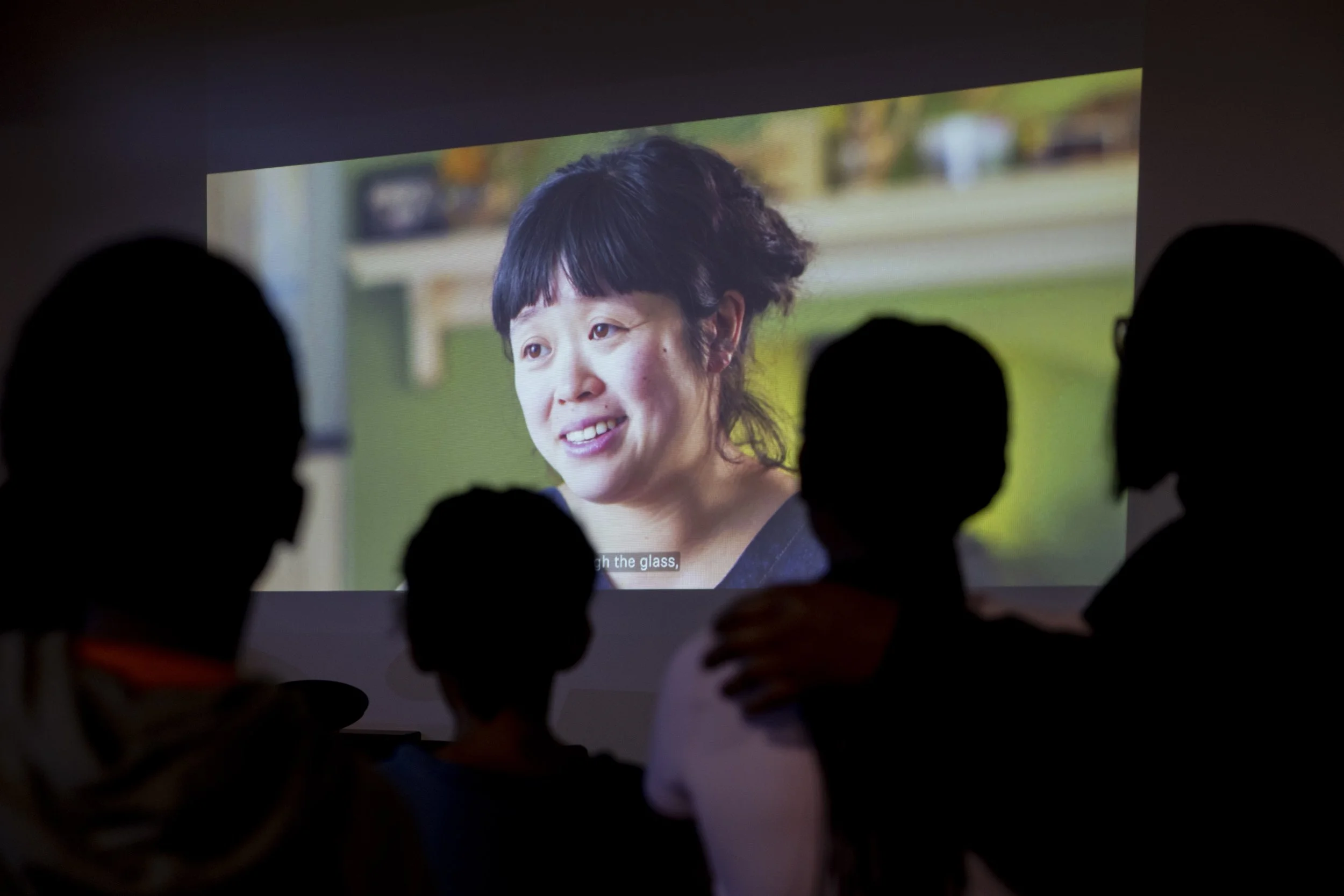   Participants silhouetted against film projection at Olympias Music Foundation event in Manchester – documentary photography by David Oates  