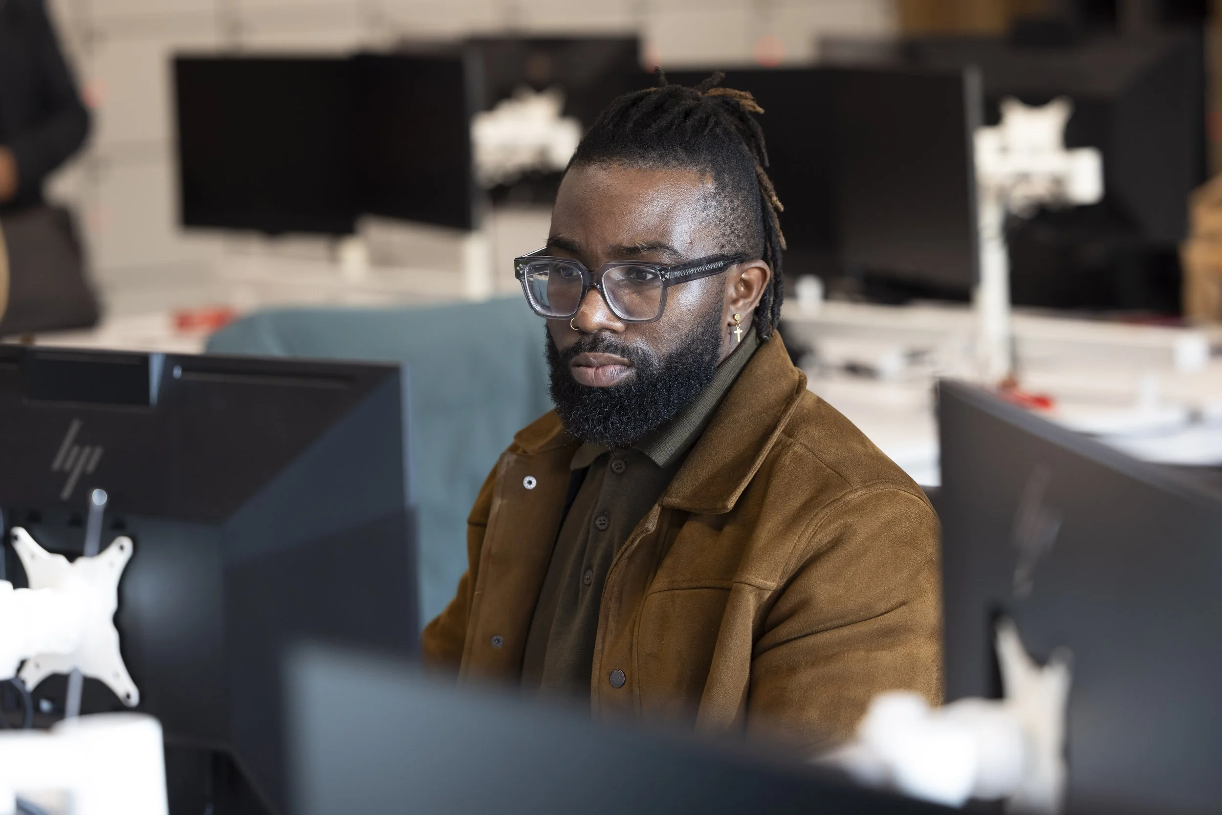 Corporate photography Manchester showing young Black male employee working at multi-screen workstation in tech office