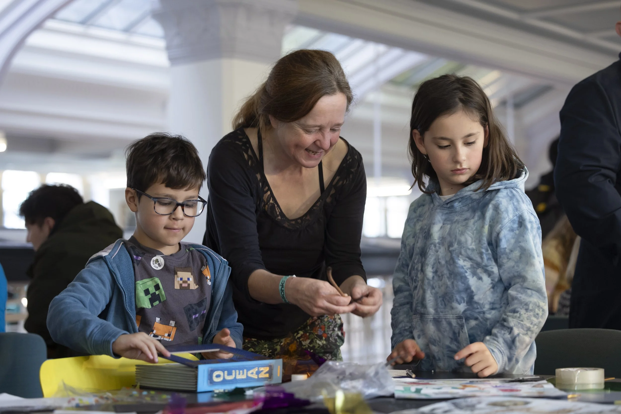 Volunteer leading craft activity with children during family workshop at EarthSonic Live, Manchester Museum
