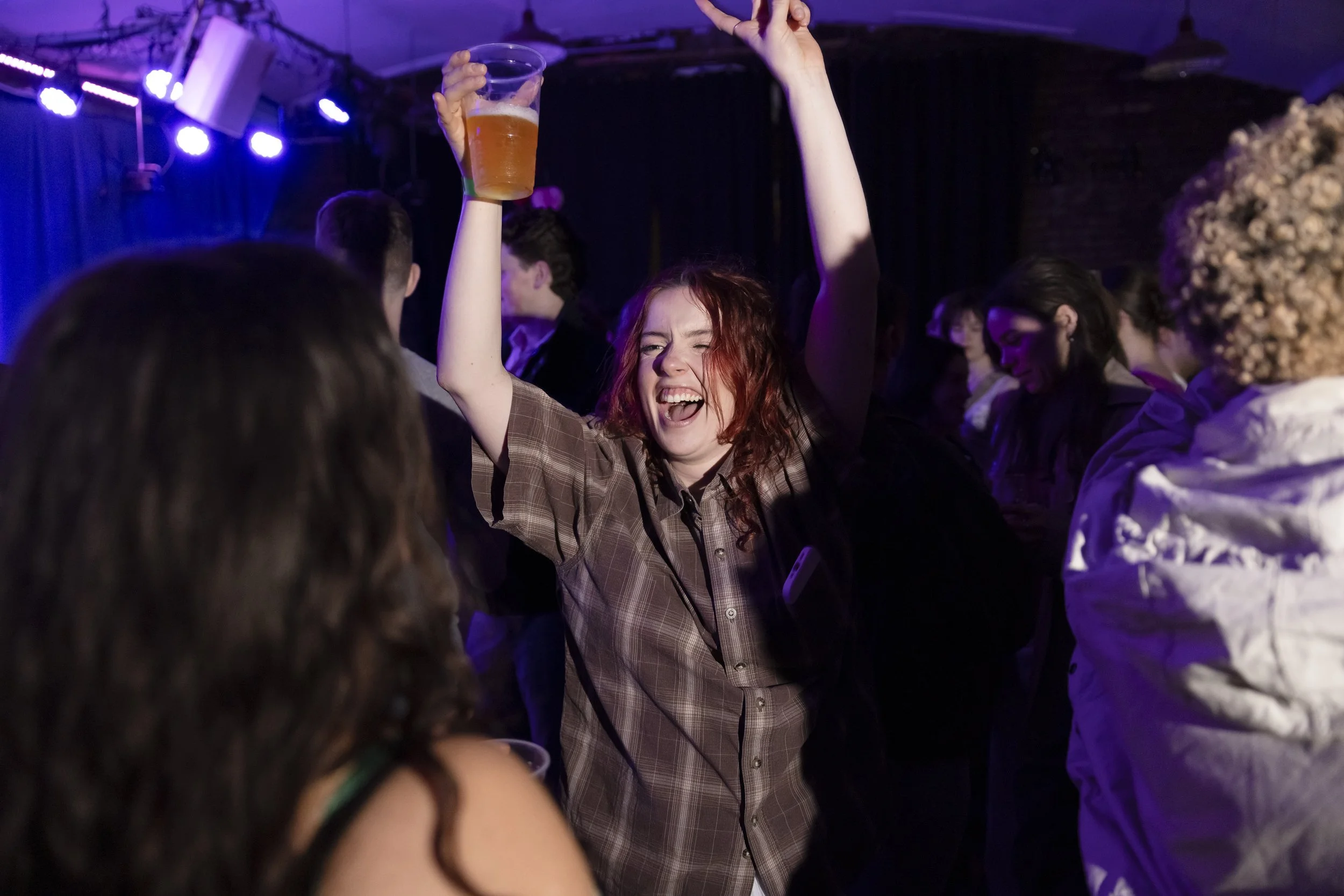 Young person dancing with hands raised during energetic Manchester club night