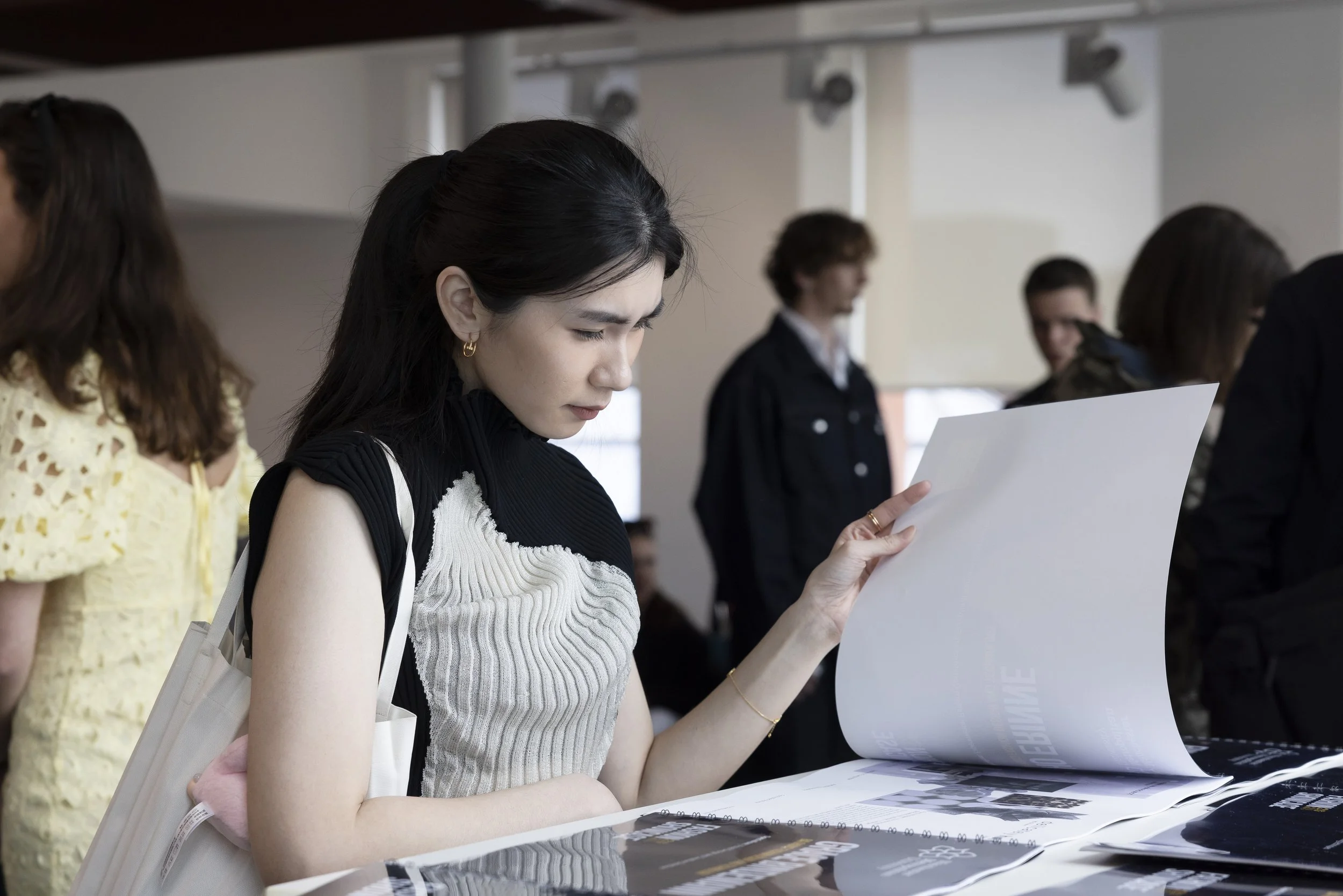 Young fashion student reviewing a portfolio of student work during Manchester Fashion Institute showcase at Manchester Metropolitan University.