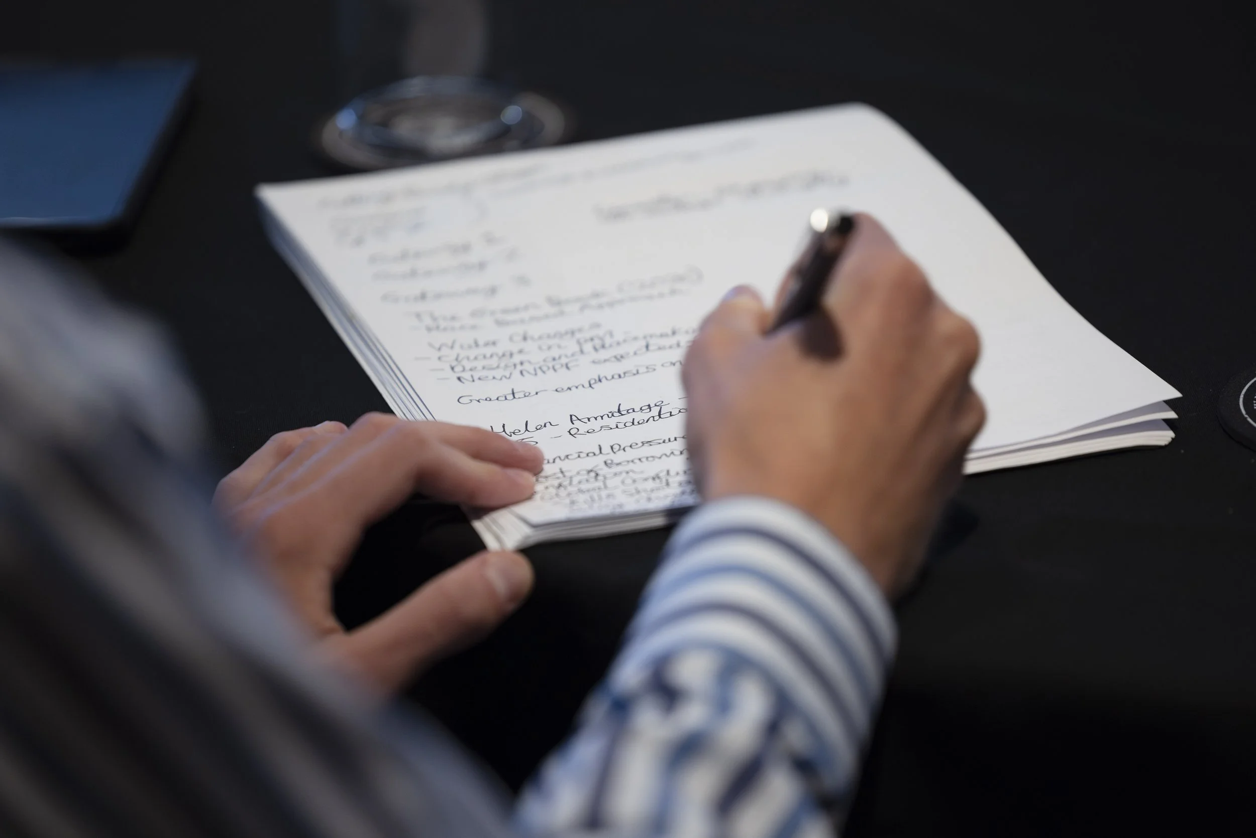 Close-up of attendee taking notes during a residential design seminar in Manchester