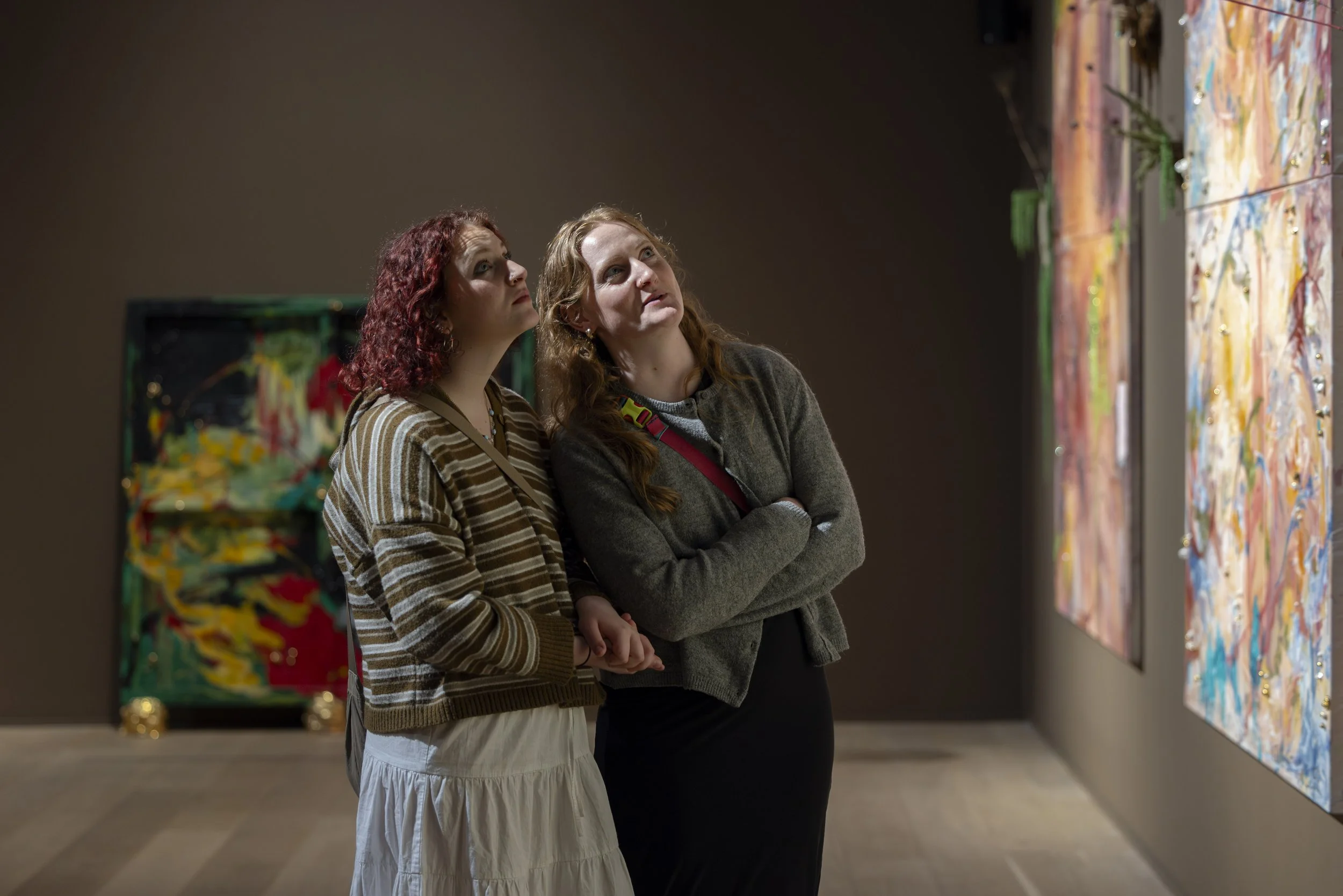 Two women looking up at contemporary artwork inside exhibition at Whitworth Art Gallery.