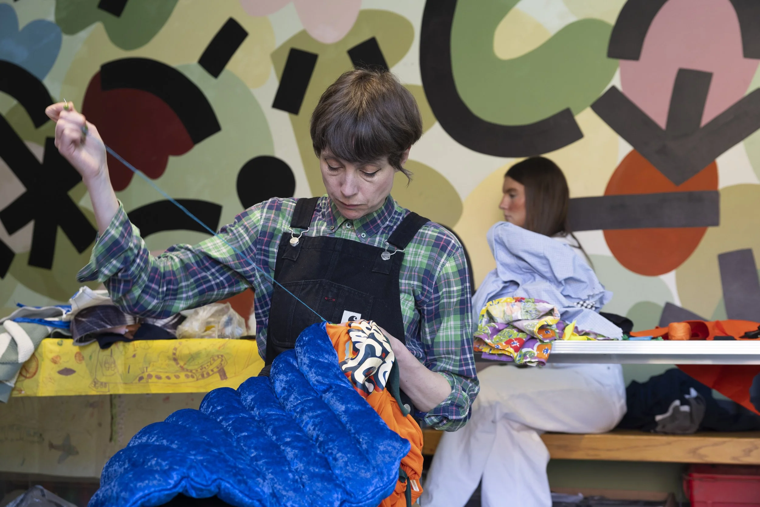 Tutor from Manchester Metropolitan University’s Institute of Fashion sewing during an upcycling workshop at The Whitworth, Manchester, hands-on textile and fashion practice within contemporary art setting