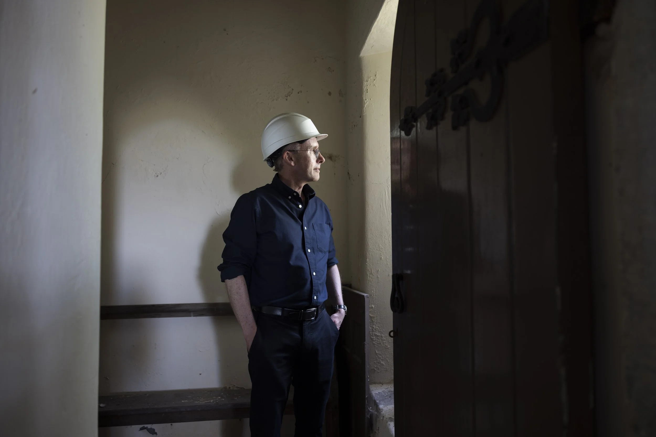 David Farrington standing inside St Tyfrydog’s Church and looking out through one of its windows.