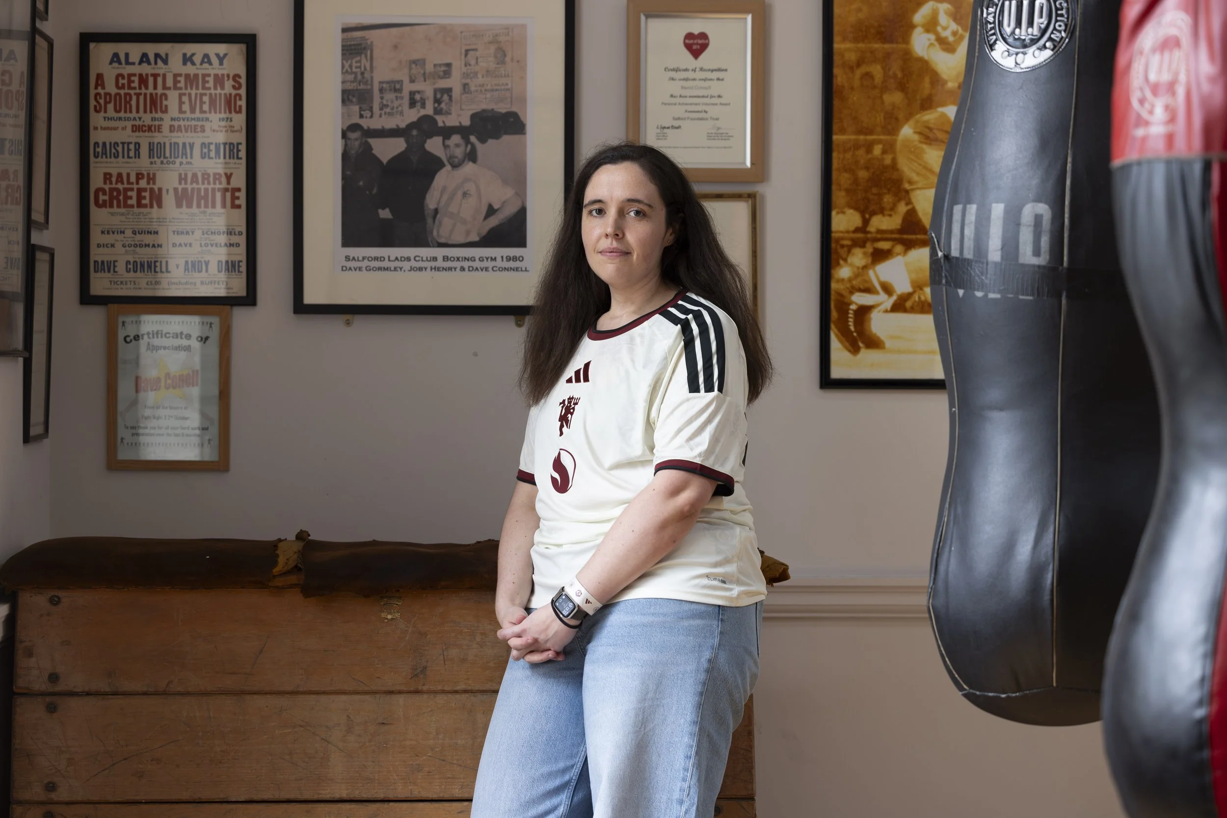 A female Manchester United fan wearing the new third shirt stands inside the boxing gym at Salford Lads & Girls Club.