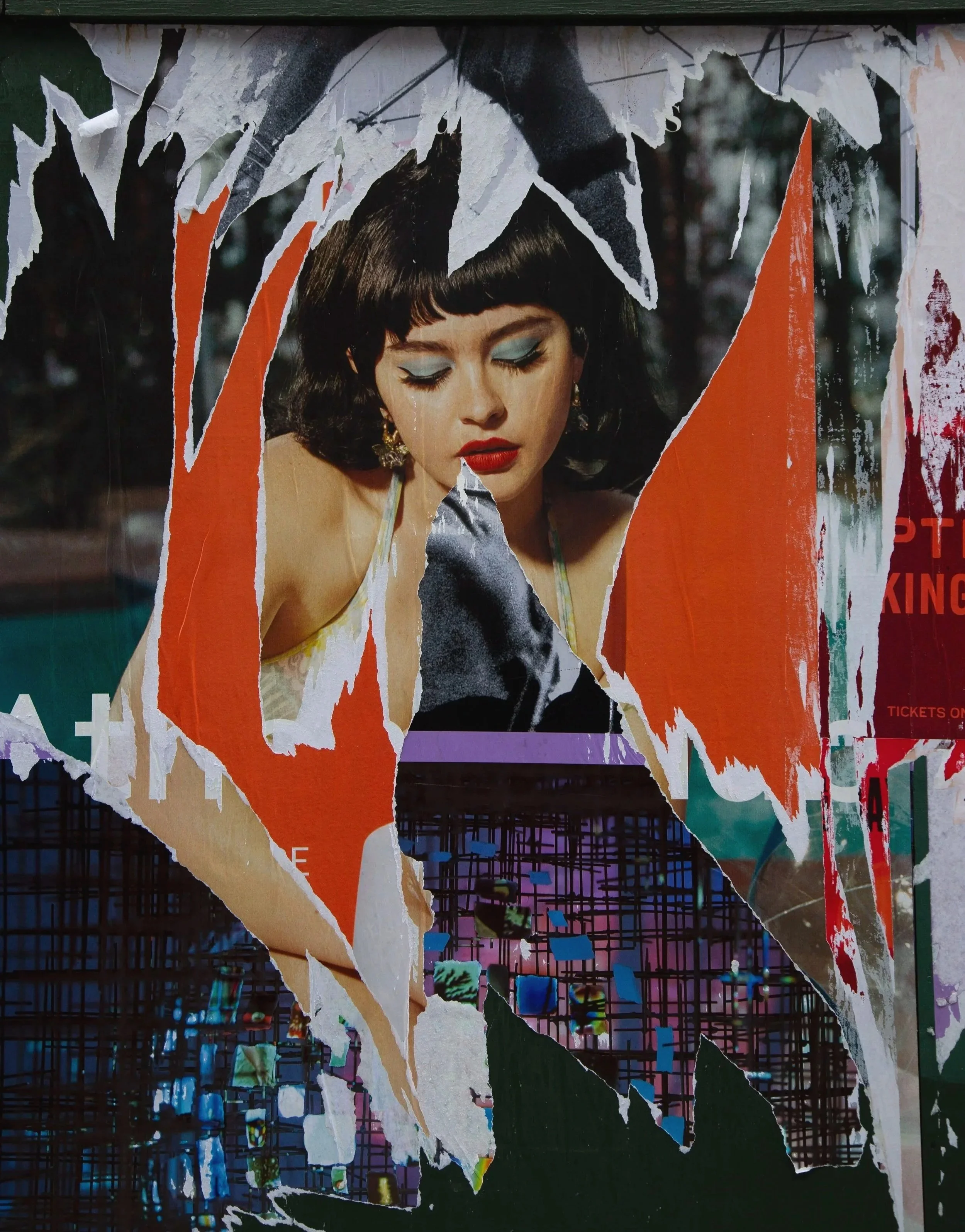 A torn poster featuring a woman with dark hair, blue eye makeup, and red lipstick, with a background of colorful grid-like patterns.