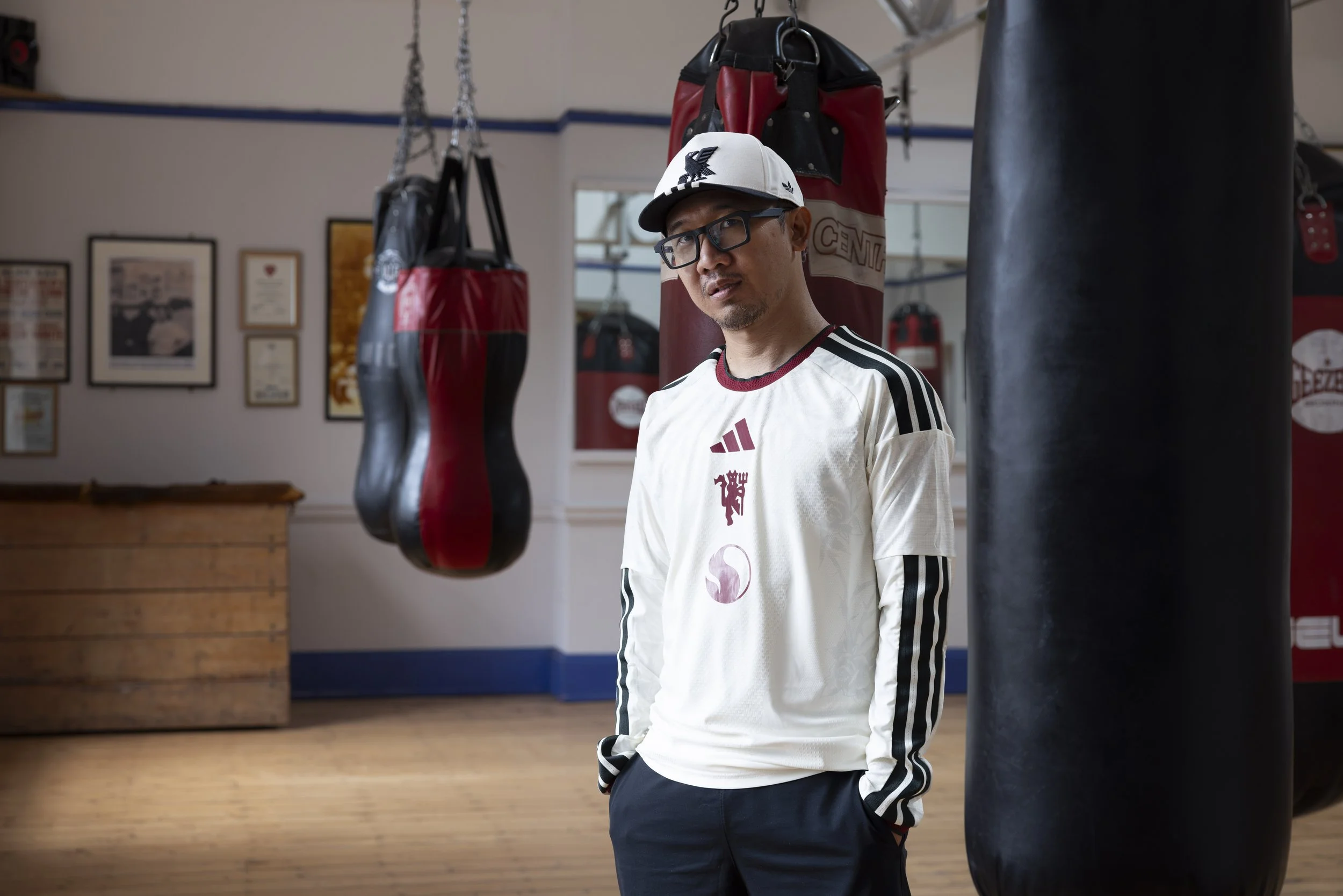 A Manchester United fan wearing the new third shirt stands among the boxing bags inside the gym at Salford Lads & Girls Club.