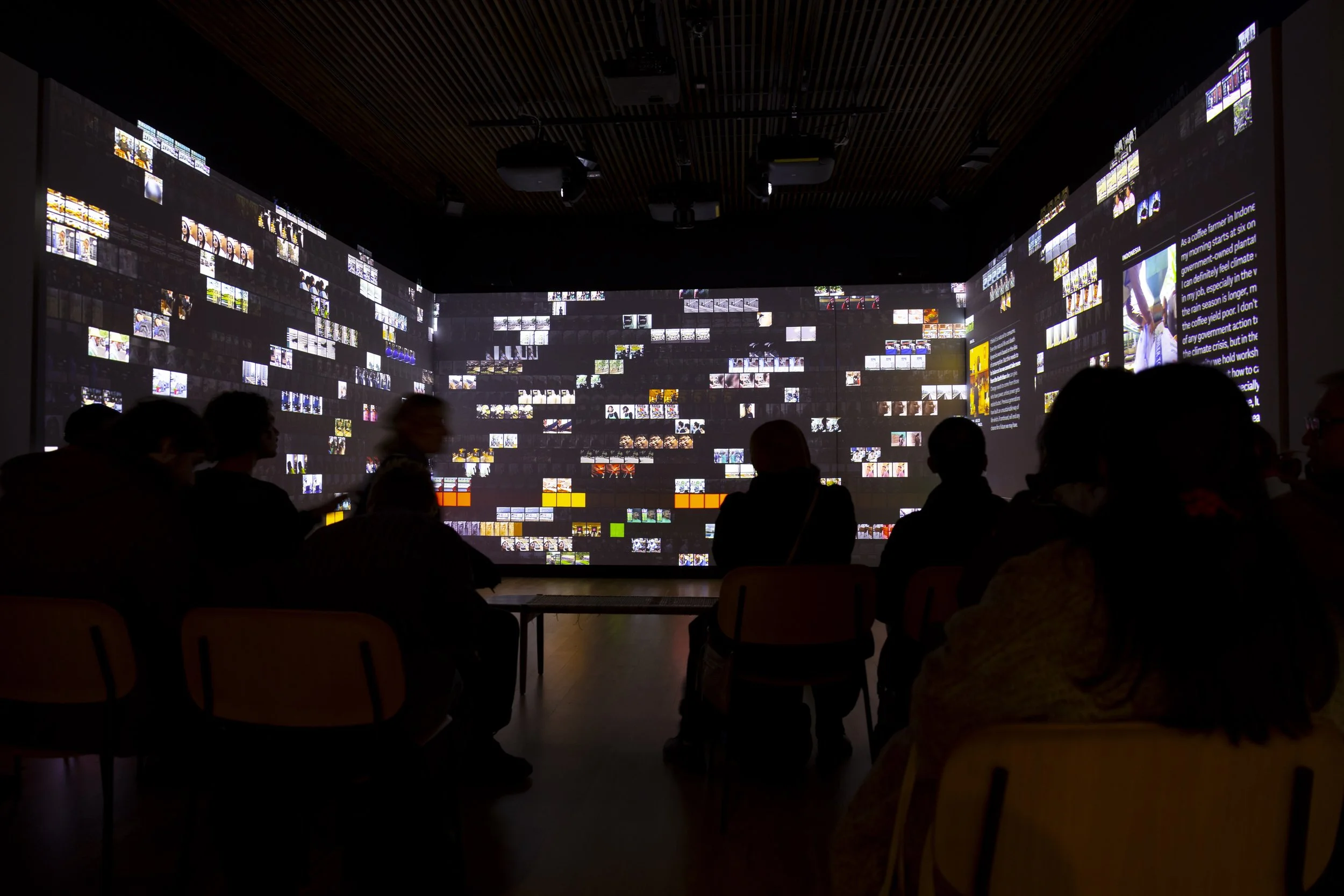Crowd silhouetted against large-scale video installation during immersive artwork at EarthSonic Live, Manchester Museum
