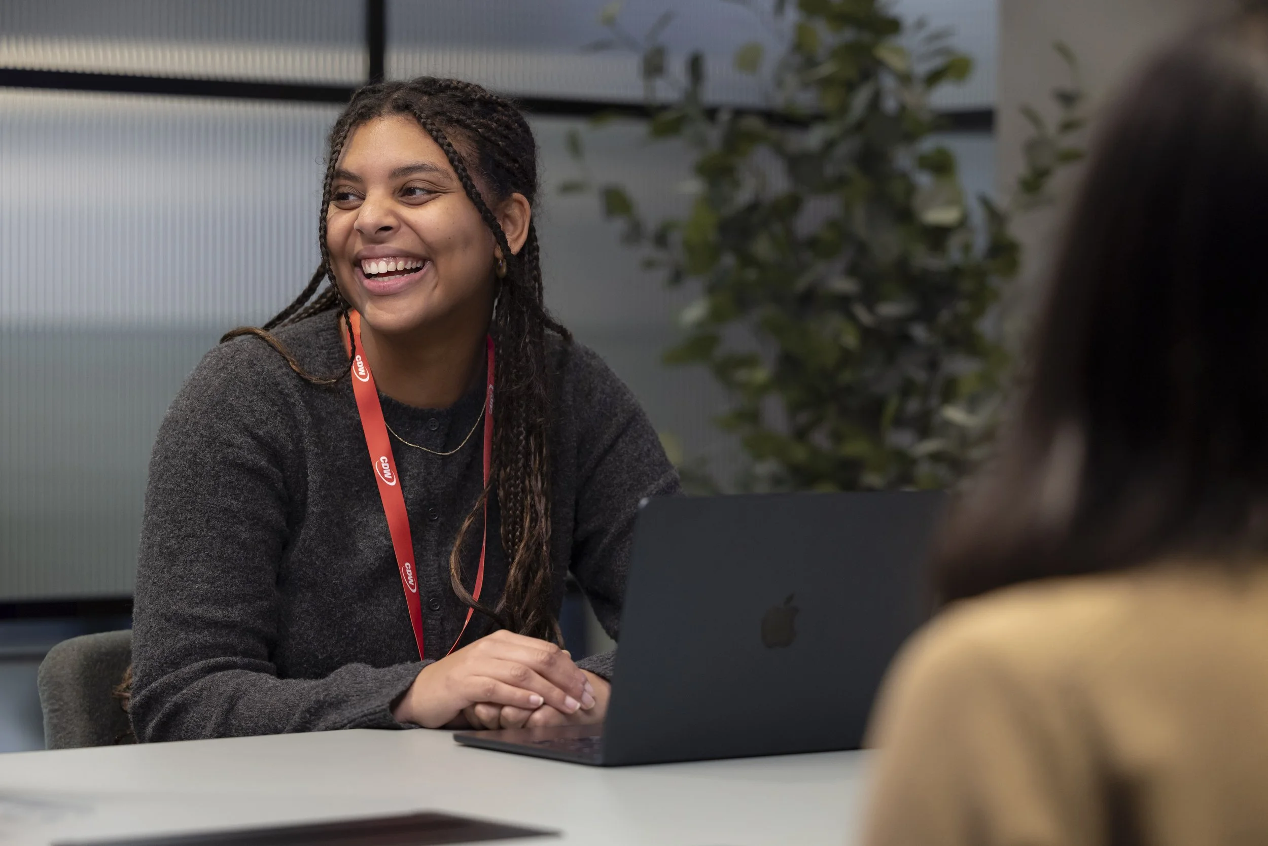 Manchester office photography of female employee laughing while working on Apple computer