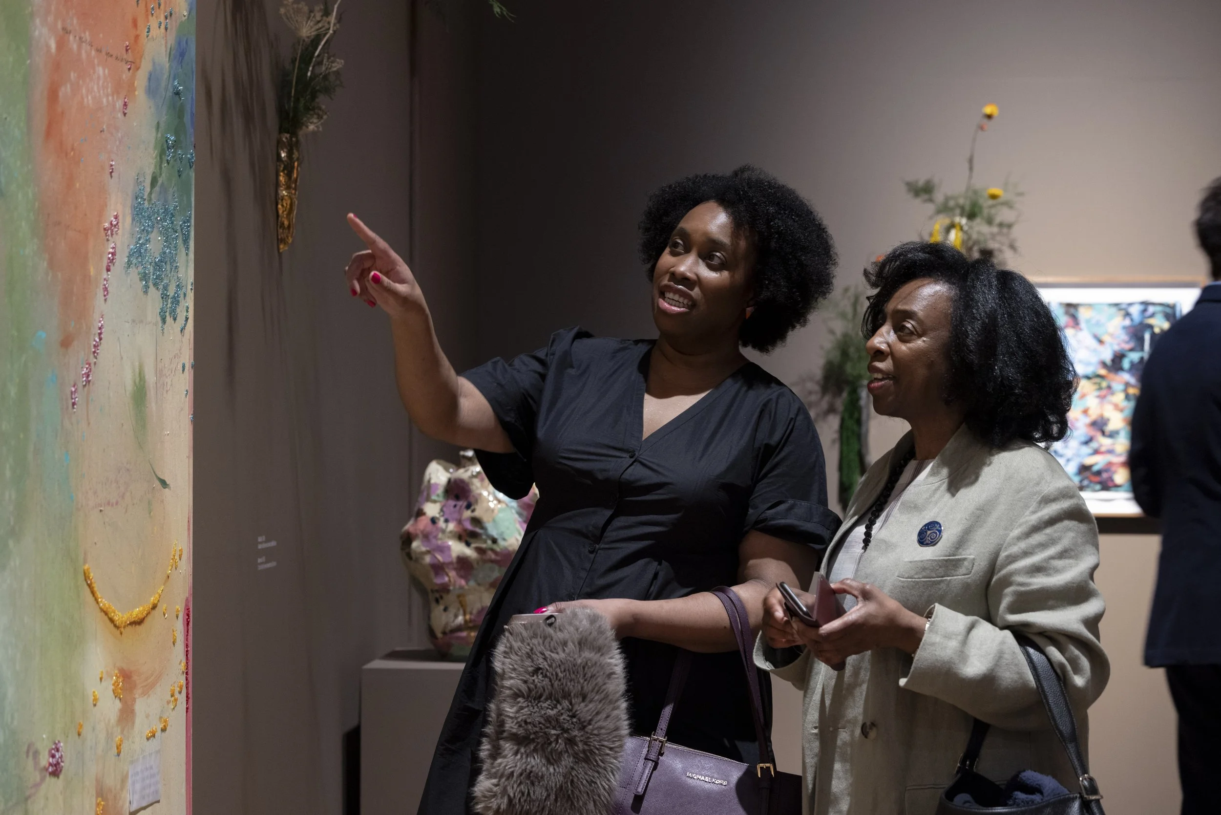 Two women observing and gesturing toward artwork during exhibition opening at Whitworth Art Gallery.
