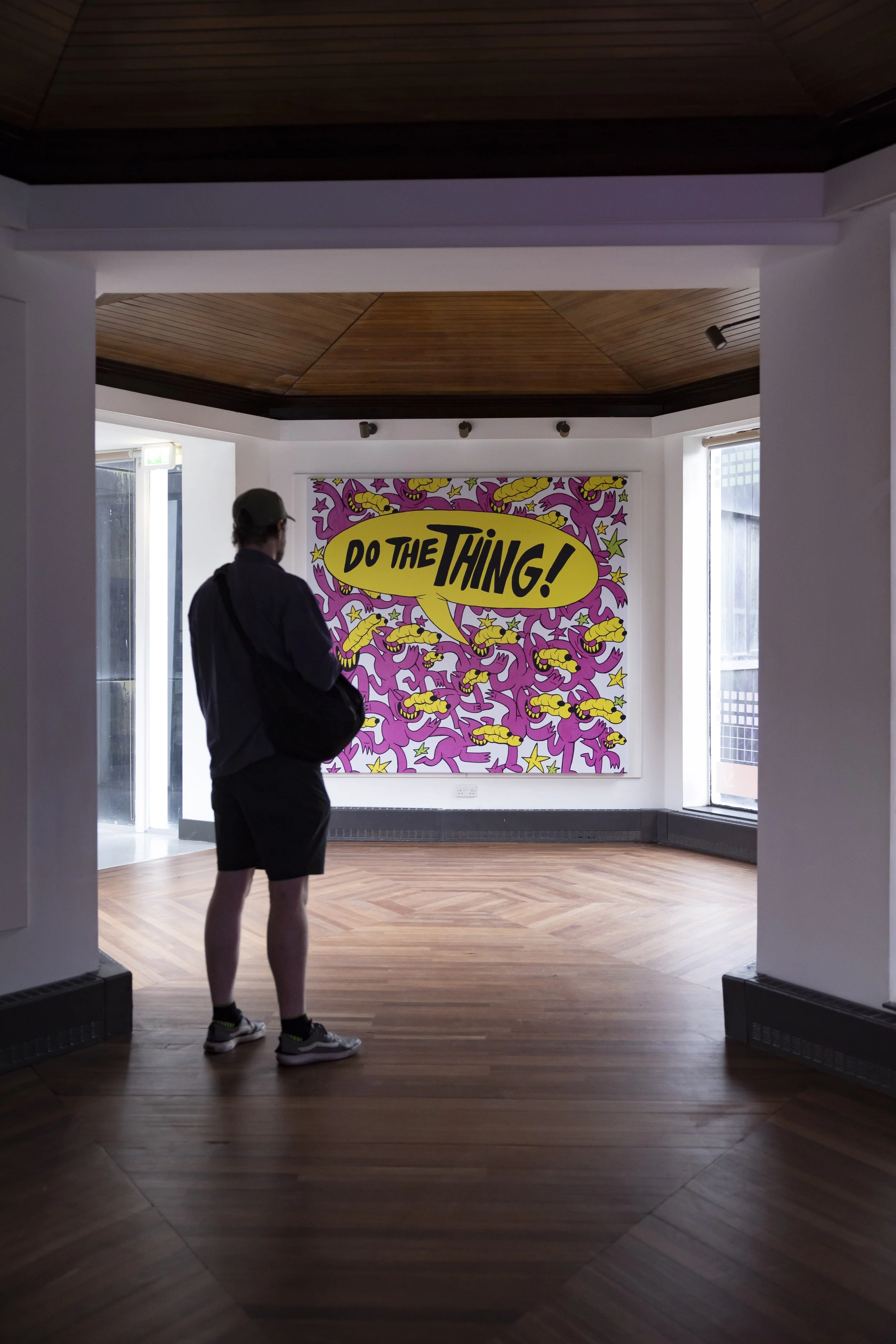 A person viewing a large, colorful "DO THE THING!" pop-art painting at the Manchester School of Art Degree Show 2026.