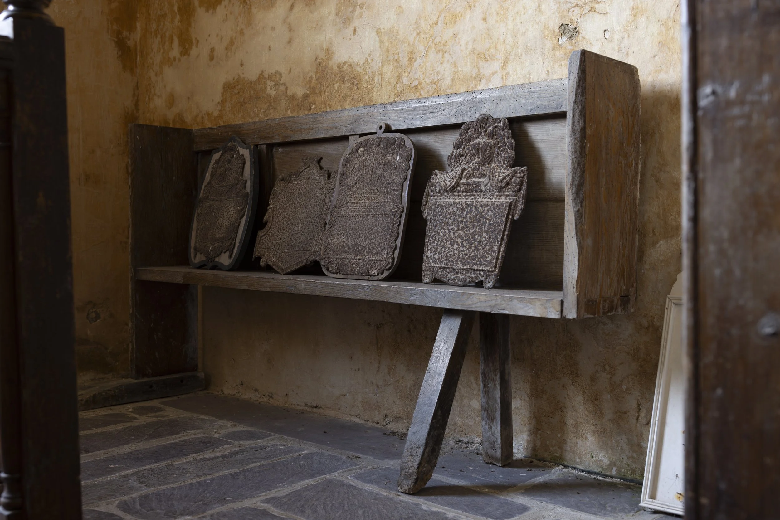 Historic cast iron memorial pieces collected from gravestones and displayed on a pew inside St Baglan’s Church.