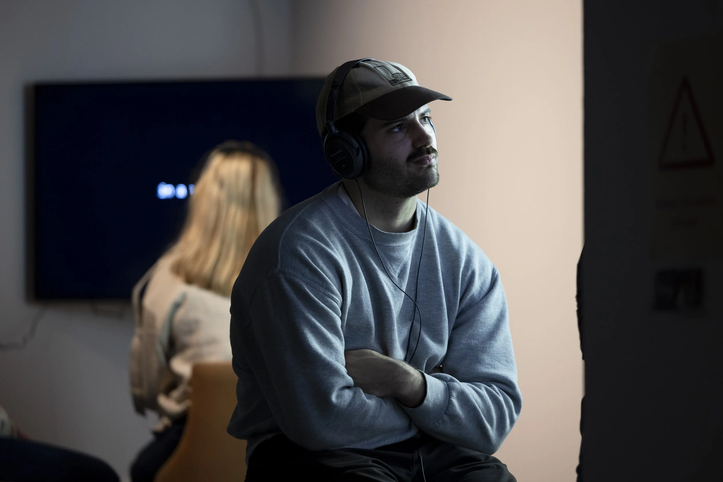 Young man wearing headphones and watching a video projection at Manchester Metropolitan University's More to Come postgraduate degree show.