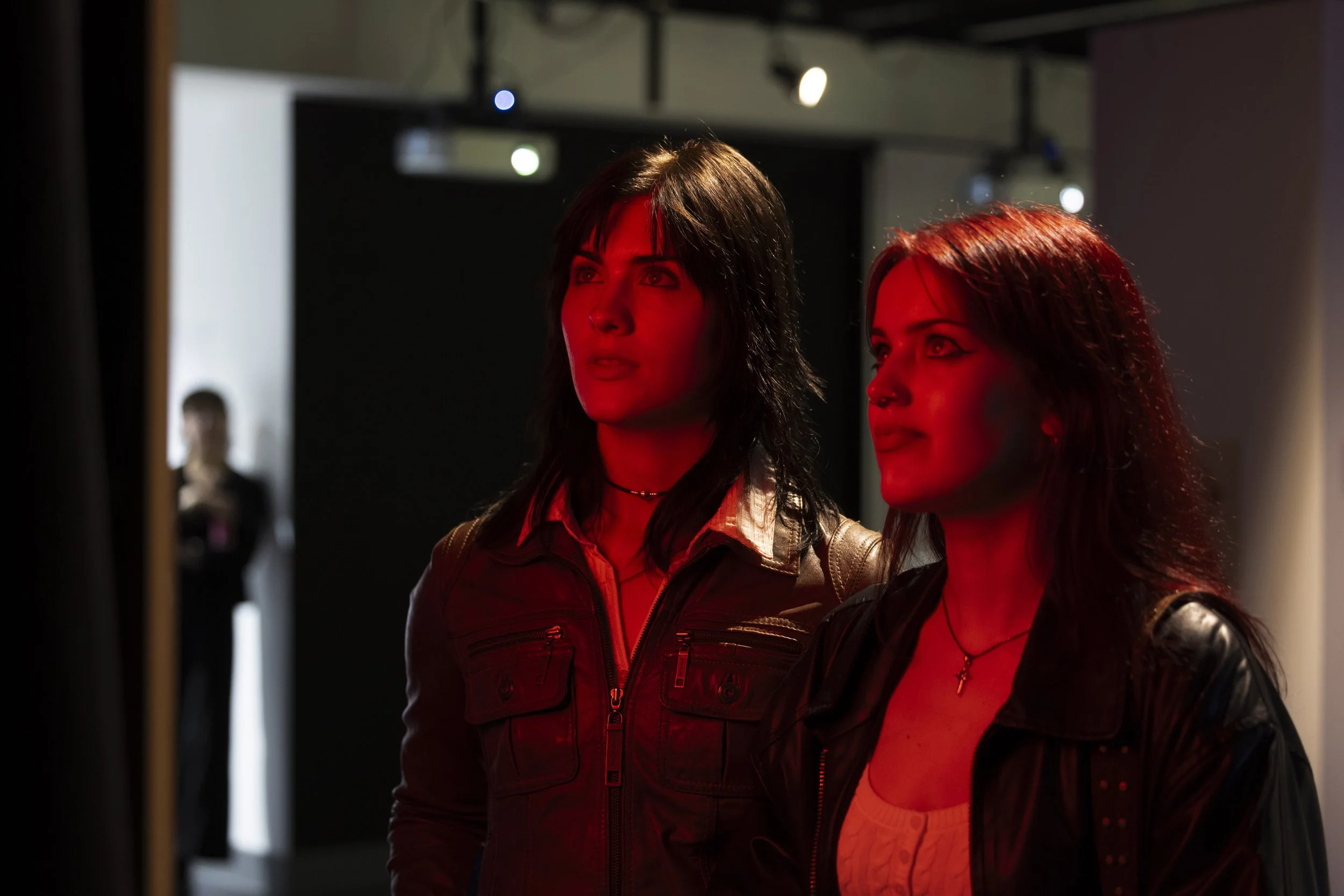 Two women bathed in red light look at an artwork in the Moulders Gallery during Manchester Metropolitan University's More to Come exhibition.